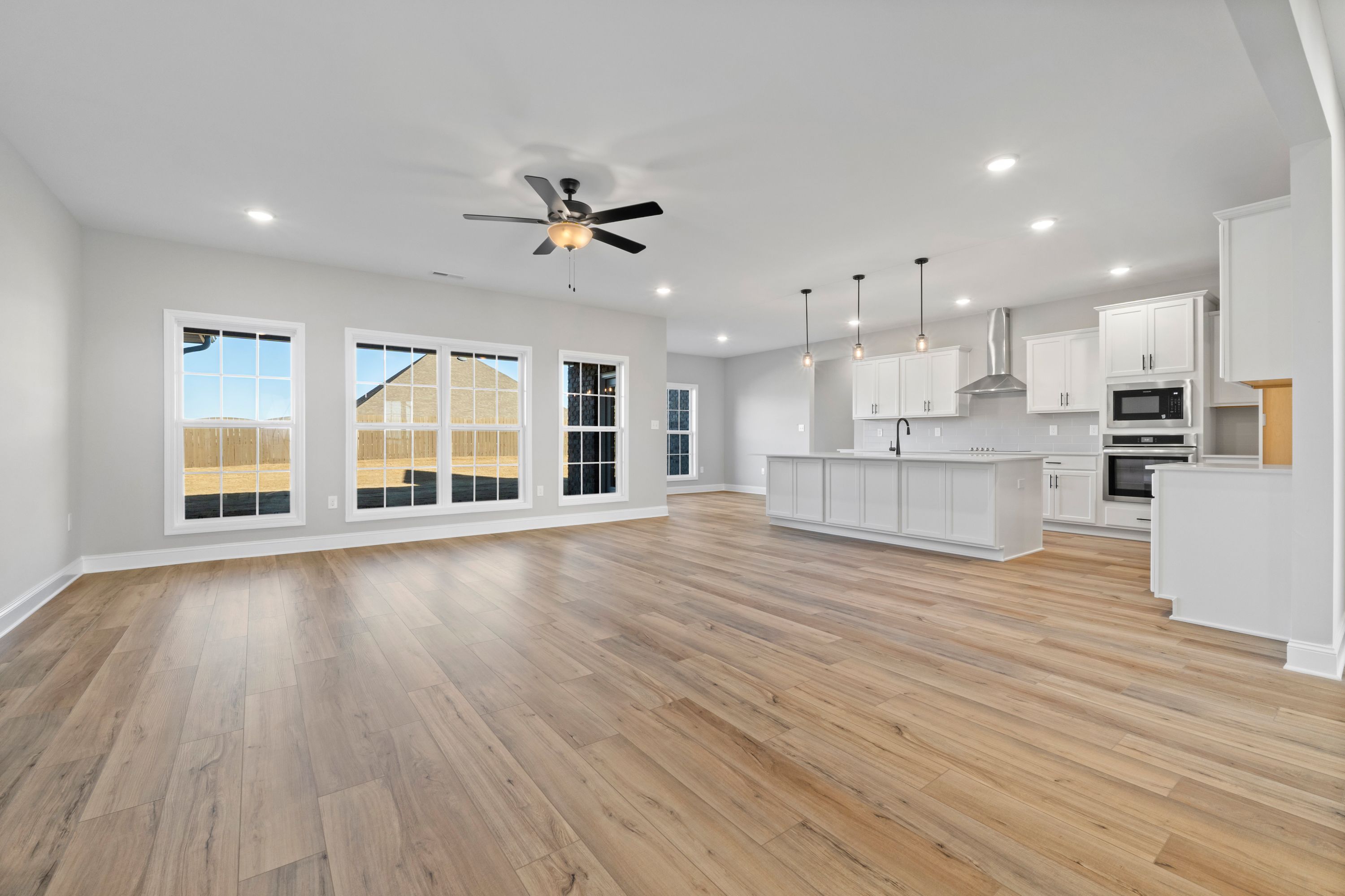 Spacious open-concept kitchen and living area in The Valencia by Davidson Homes, Meridianville AL, with white shaker cabinets, large island, hardwood floors, and large windows