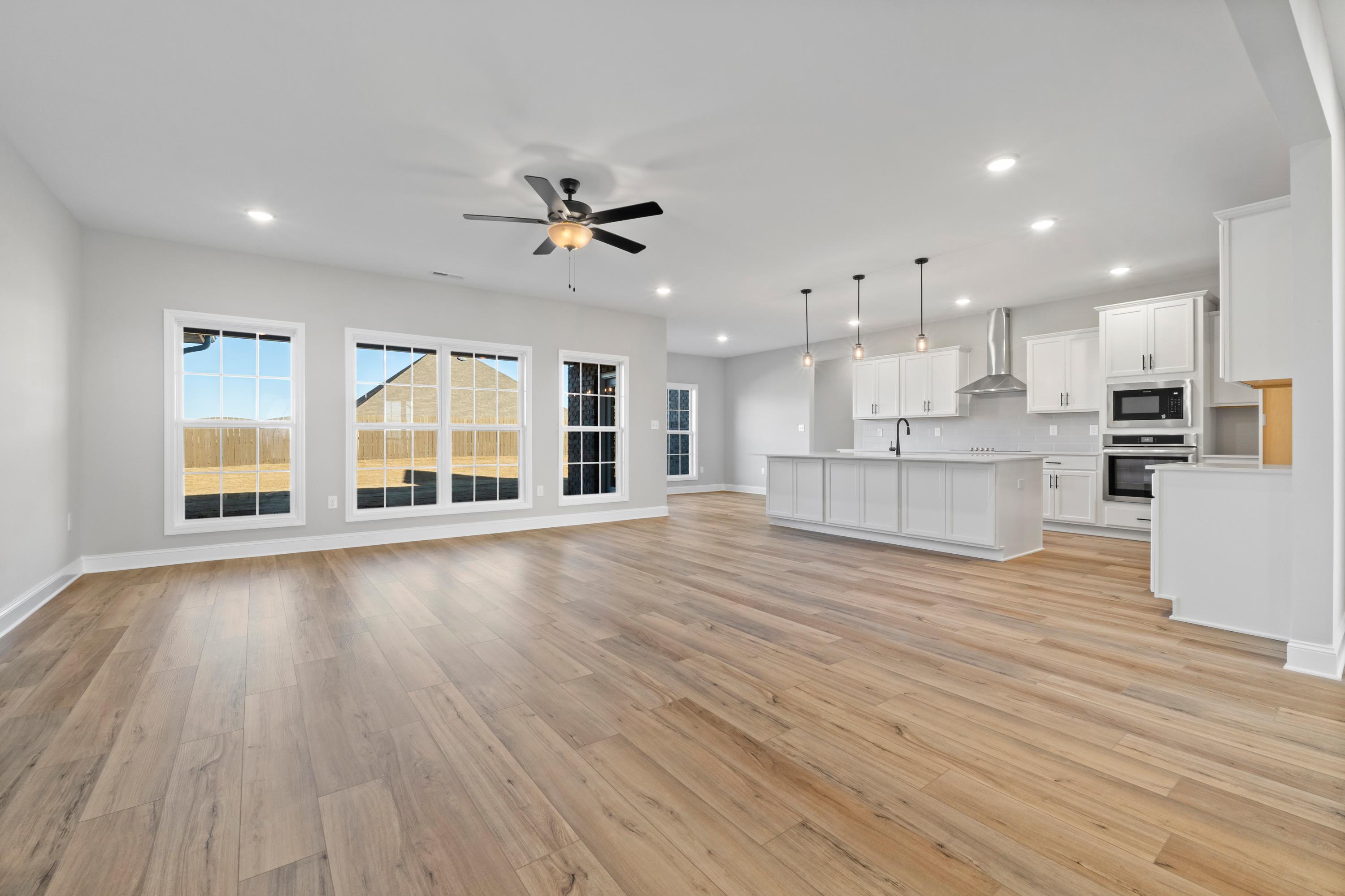 Spacious open-concept kitchen and living area in The Valencia by Davidson Homes, Meridianville AL, with white shaker cabinets, large island, hardwood floors, and large windows