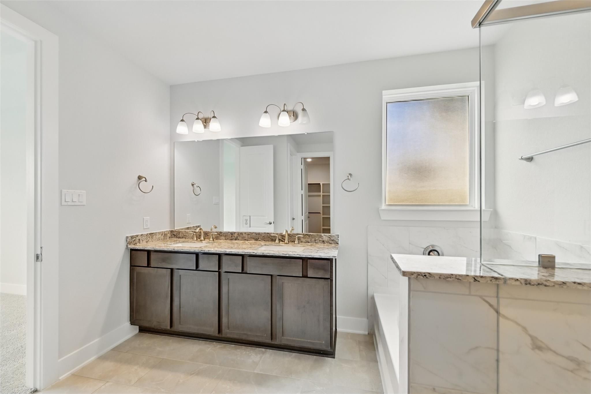 Elegant master bathroom with double granite vanity, soaking tub, and frosted window in Davidson Homes The Philip A, Lago Mar, Texas