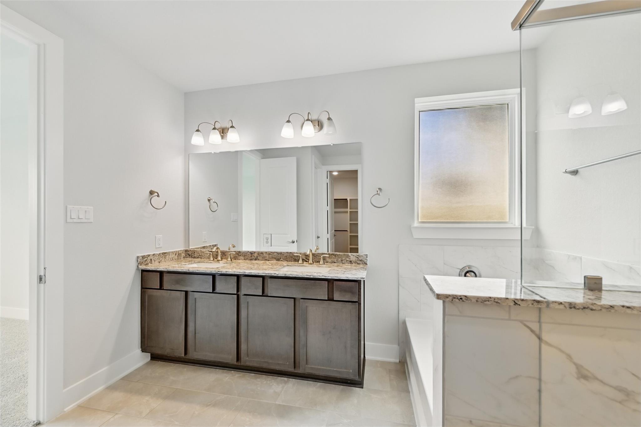 Elegant master bathroom with double granite vanity, soaking tub, and frosted window in Davidson Homes The Philip A, Lago Mar, Texas