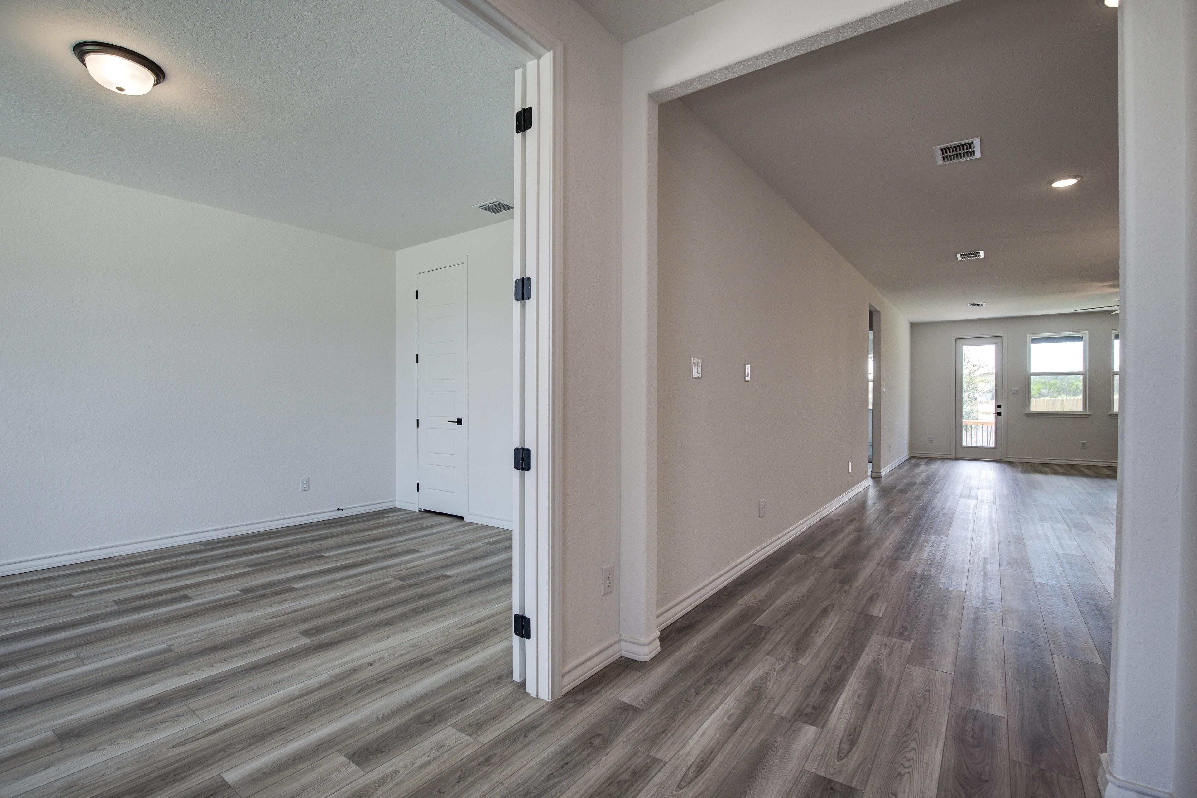 Spacious hallway in The Lanier floor plan with open double doors, gray luxury vinyl plank floors, and neutral walls leading to living area