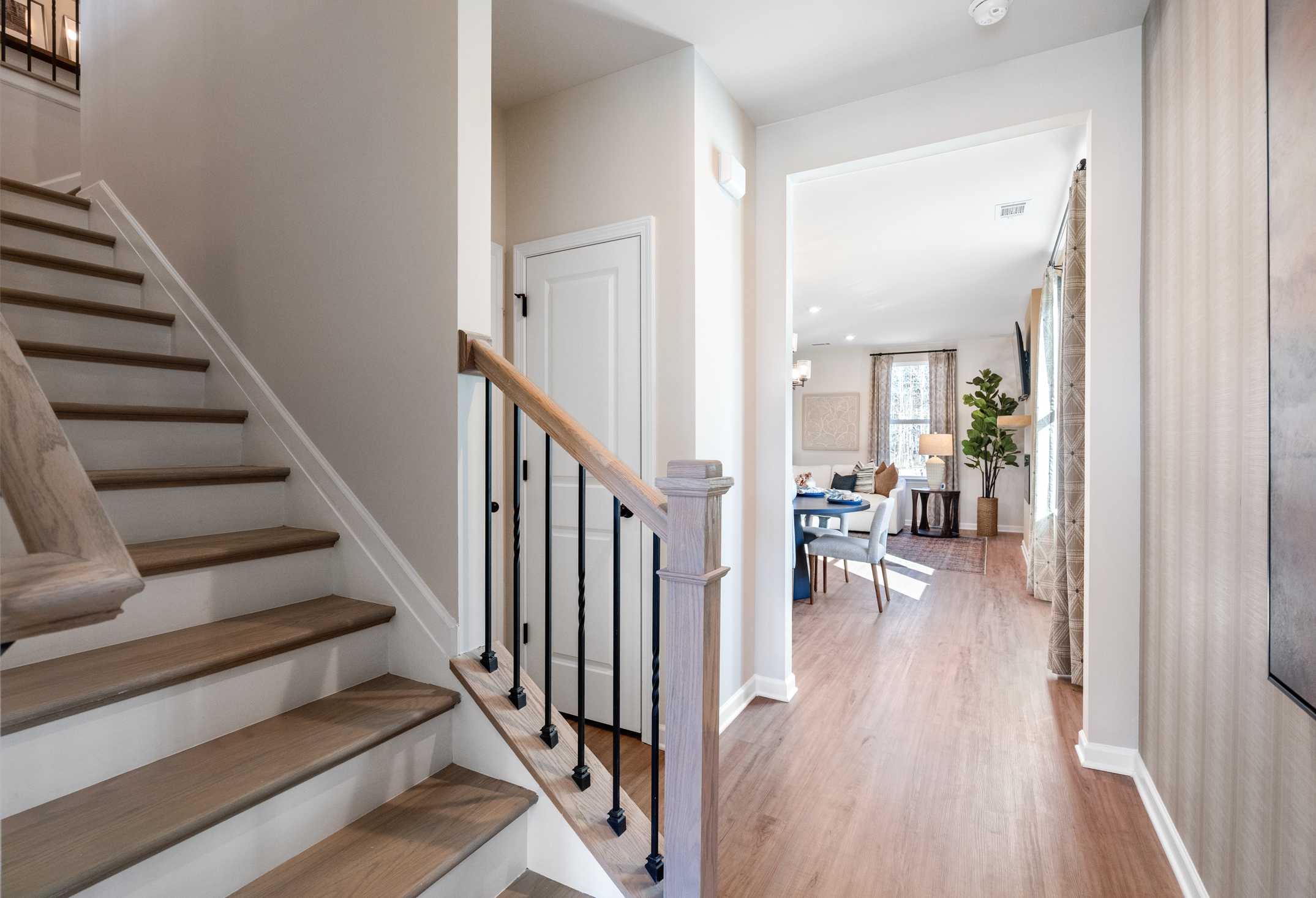 Two-story staircase in The Marion A home with wooden treads, wrought iron railing, and open hallway to dining area