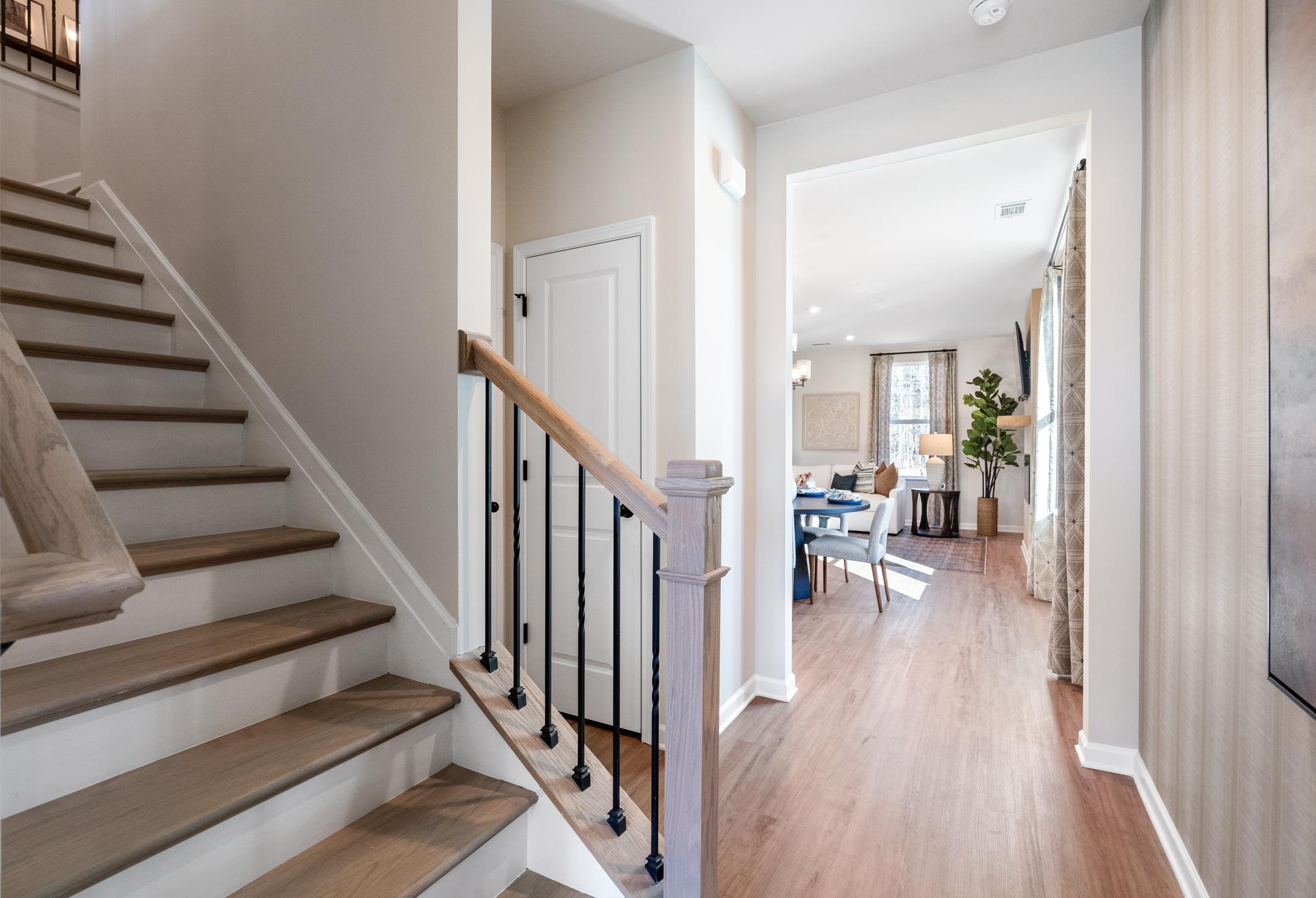 Two-story staircase in The Marion A home with wooden treads, wrought iron railing, and open hallway to dining area