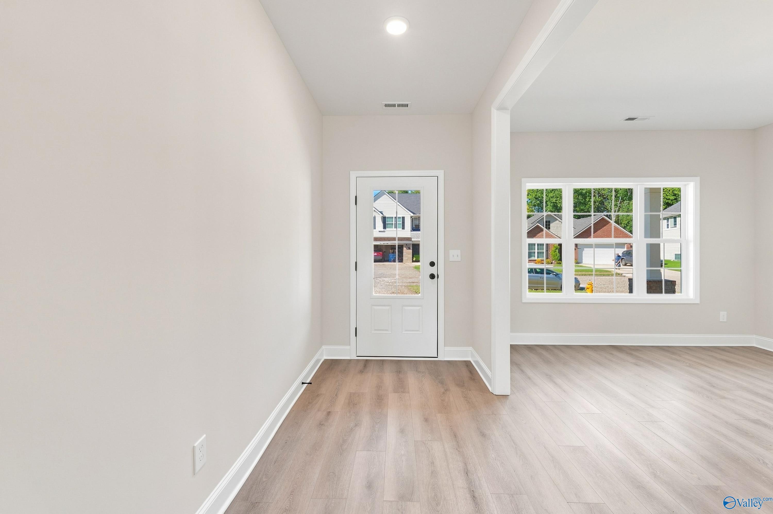 Bright entryway with glass-paneled front door and luxury vinyl plank flooring in Davidson Homes' Chelsea B plan, New Market, AL