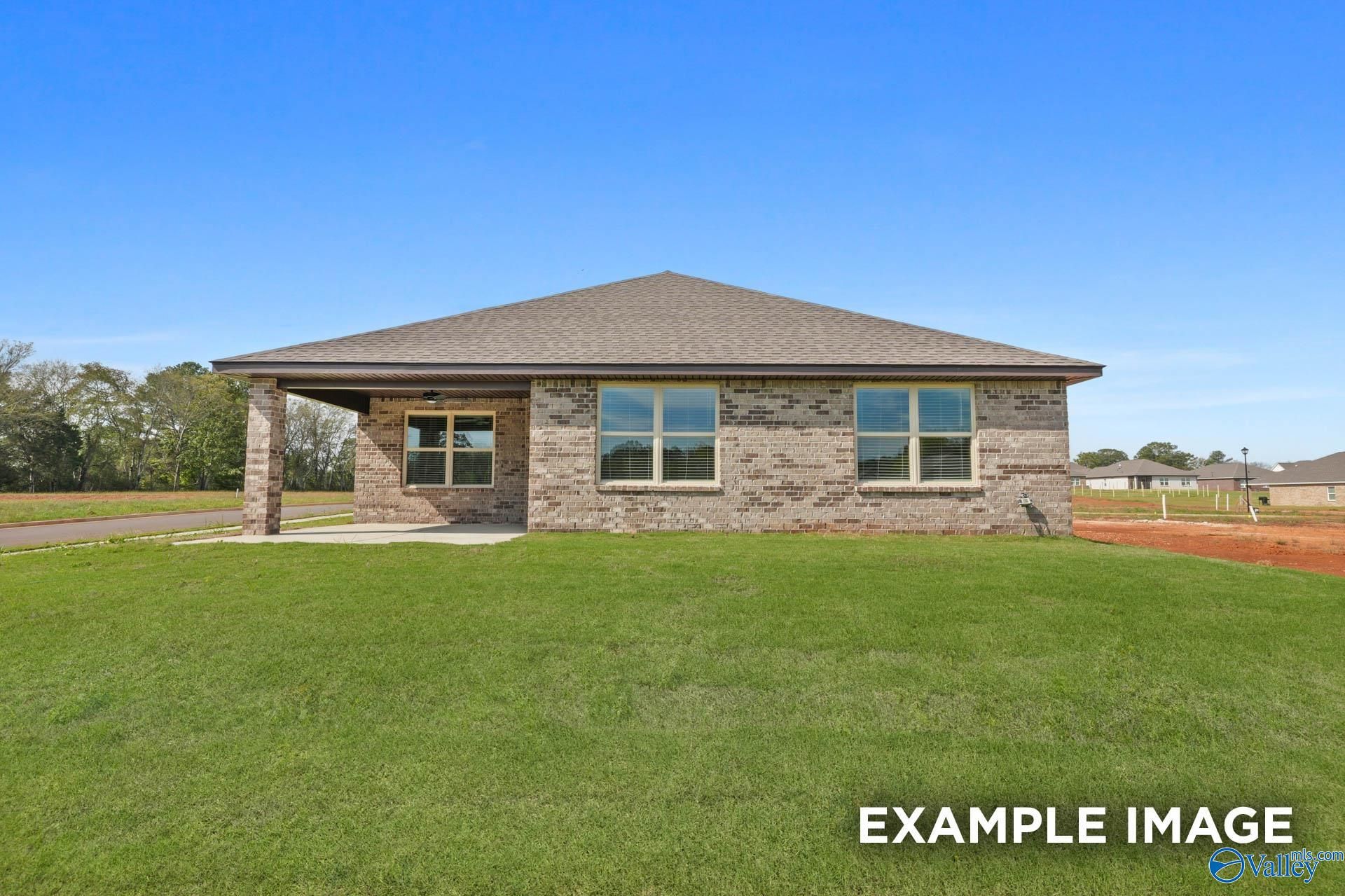 Single-story brick home with covered porch, large windows, and green lawn in Wood Trail, Toney, Alabama - The Everett B by Davidson Homes