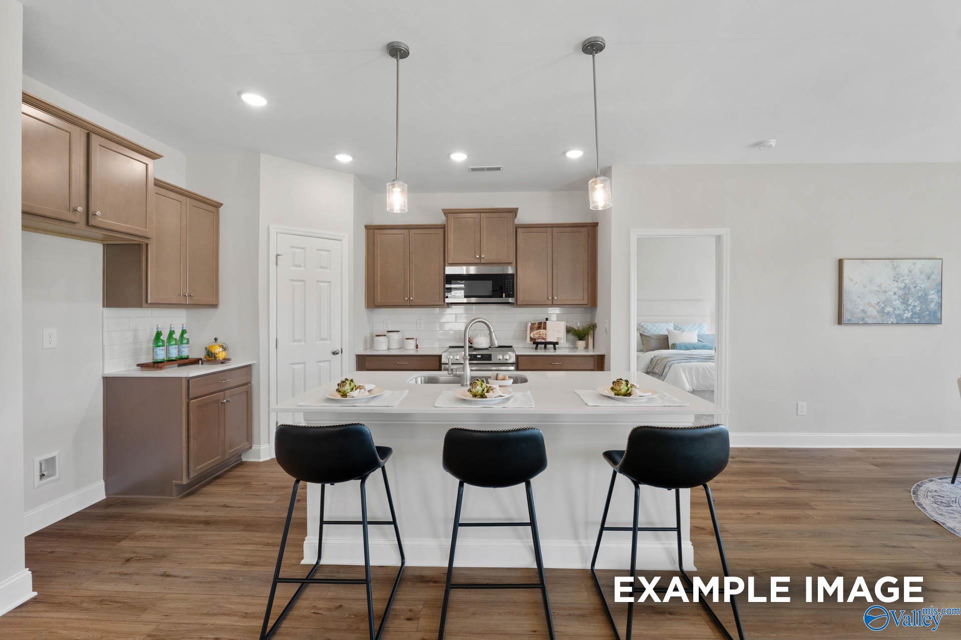 Modern kitchen with island, pendant lighting, and wood floors in The Franklin C floor plan at Heritage Lakes, New Market.