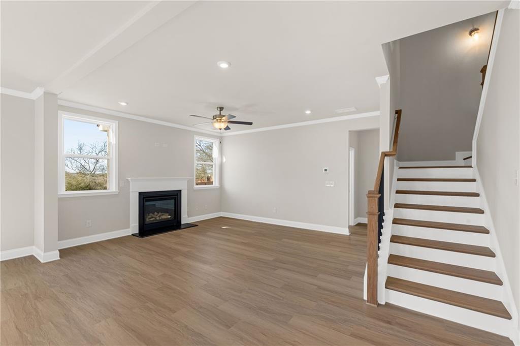 Spacious living room with gas fireplace, hardwood floors, ceiling fan, and staircase in Davidson Homes The Willow B, Hoschton, Georgia