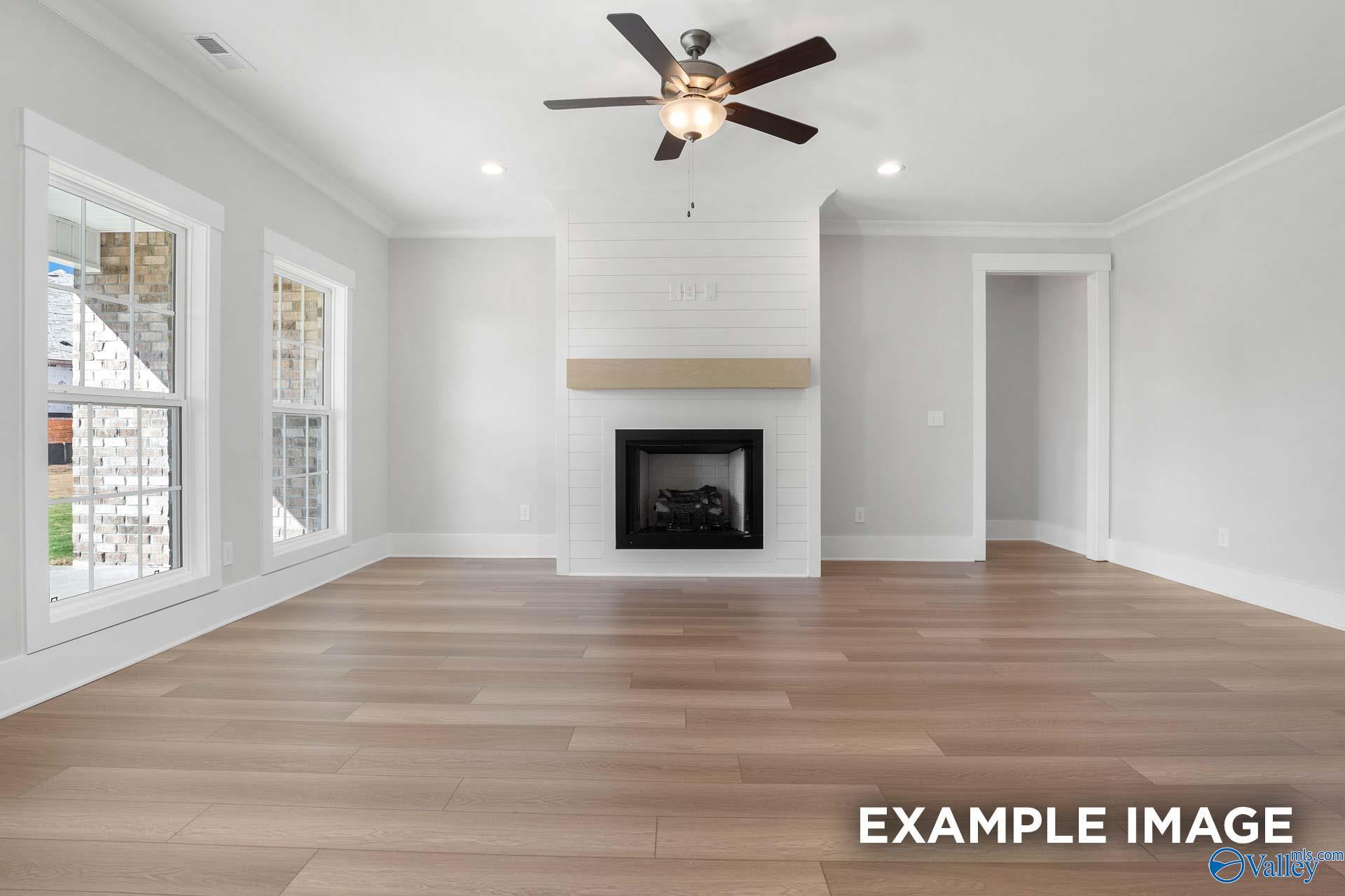 Spacious living room with shiplap fireplace, ceiling fan, and large windows in Davidson Homes The Harrison, Decatur Alabama