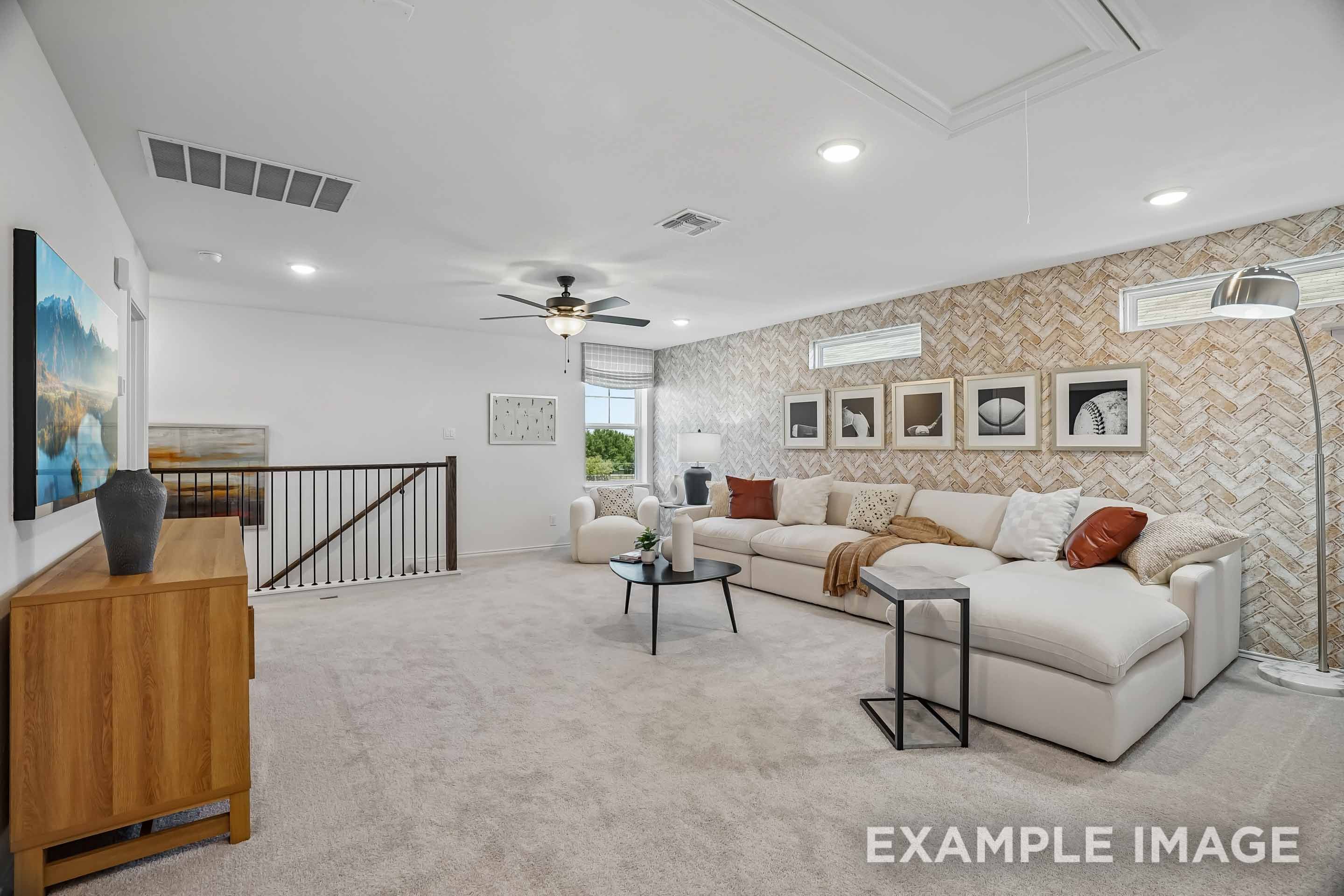 Spacious second-floor loft in The Pinecrest D featuring modern decor, plush sectional seating, and a decorative brick wall.