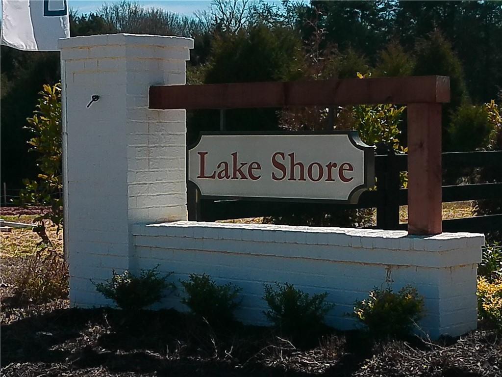 Lake Shore community entrance sign on white brick pillars with wooden accents and lush shrubs, Winder, Georgia