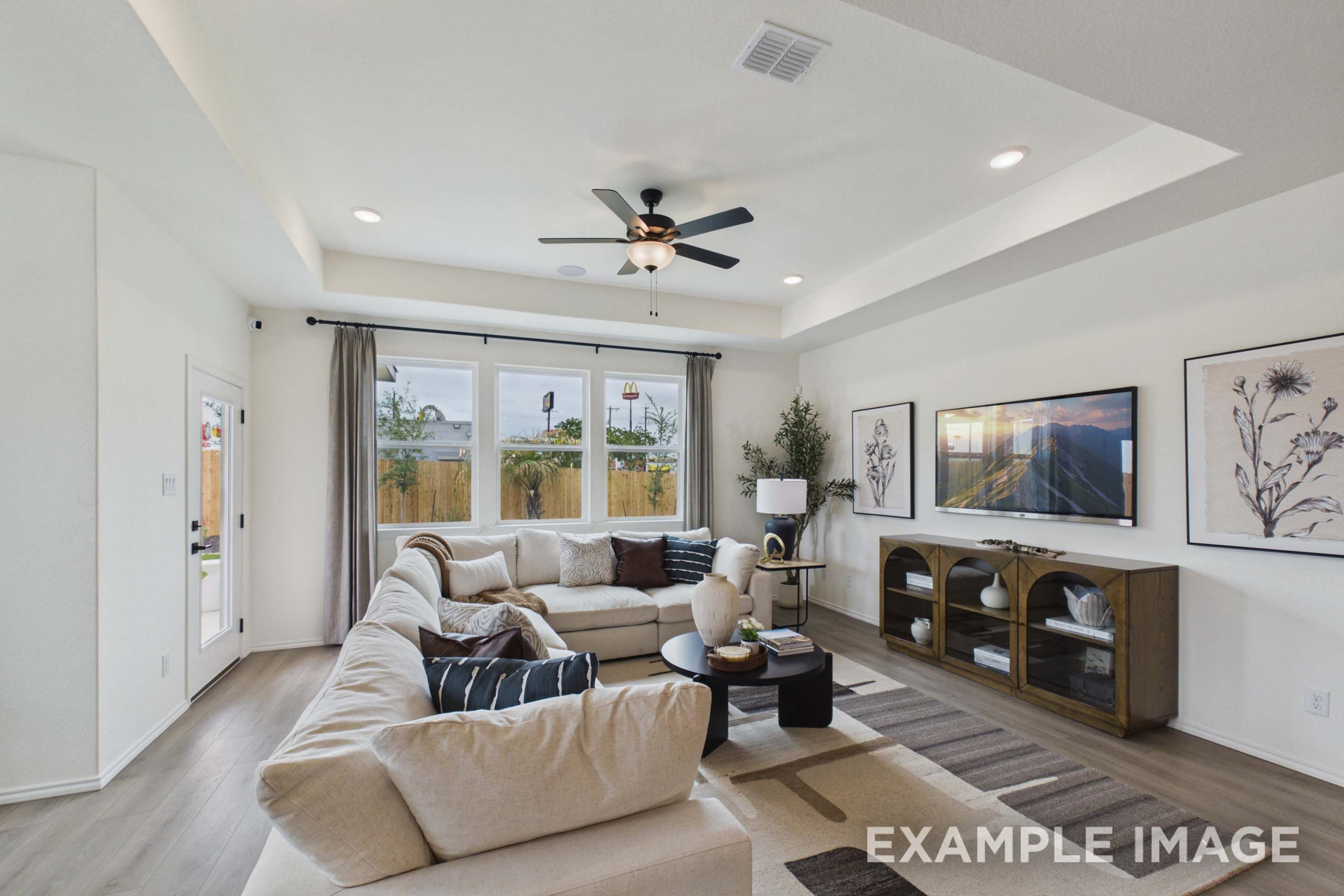 Spacious living room in The Laurel G featuring a tray ceiling, large sectional sofa, and modern decor in San Antonio, TX.