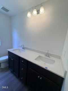 Double vanity bathroom with dark cabinets, quartz countertops, and modern lighting in The Willow B, Woodland Crossing.