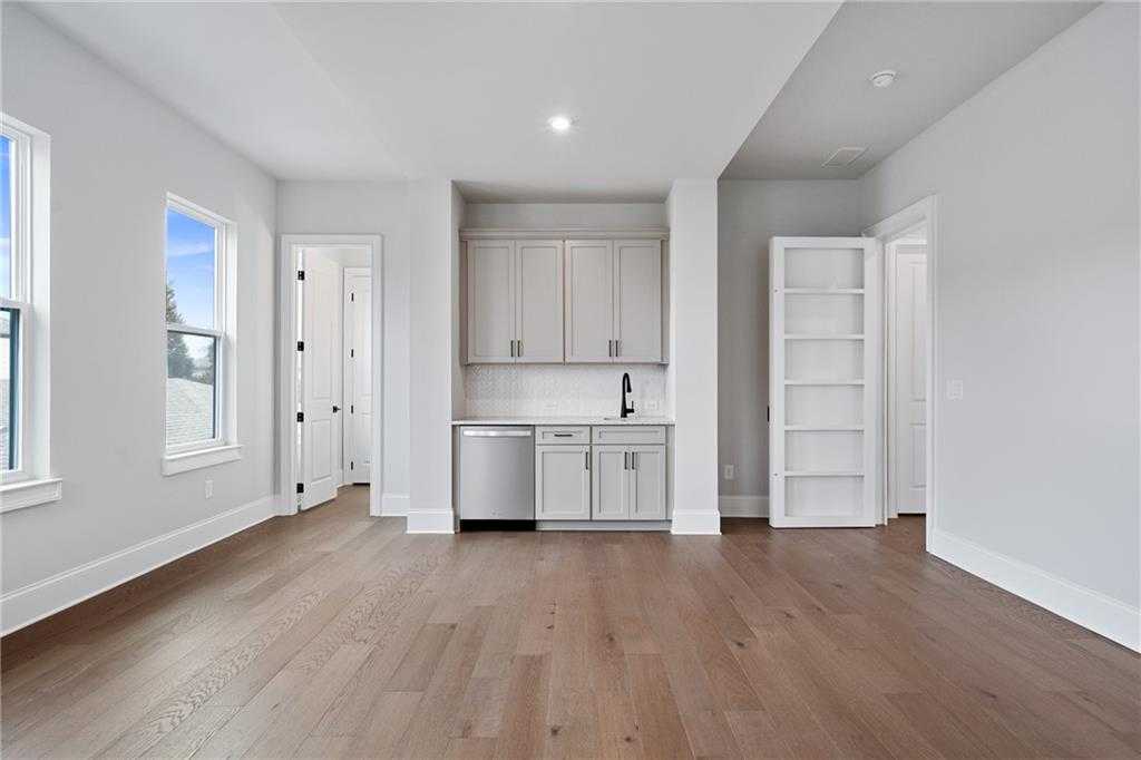 Bright butler's pantry with white cabinets, stainless sink, dishwasher, and open shelving in Davidson Homes Seaside B, Woodstock GA