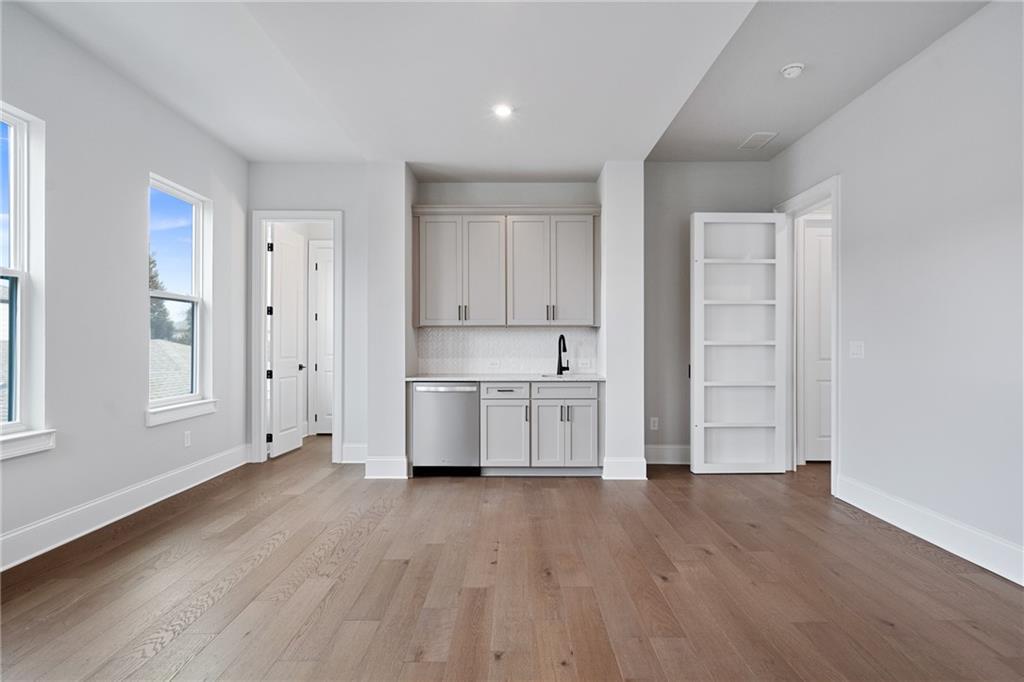 Bright butler's pantry with white cabinets, stainless sink, dishwasher, and open shelving in Davidson Homes Seaside B, Woodstock GA