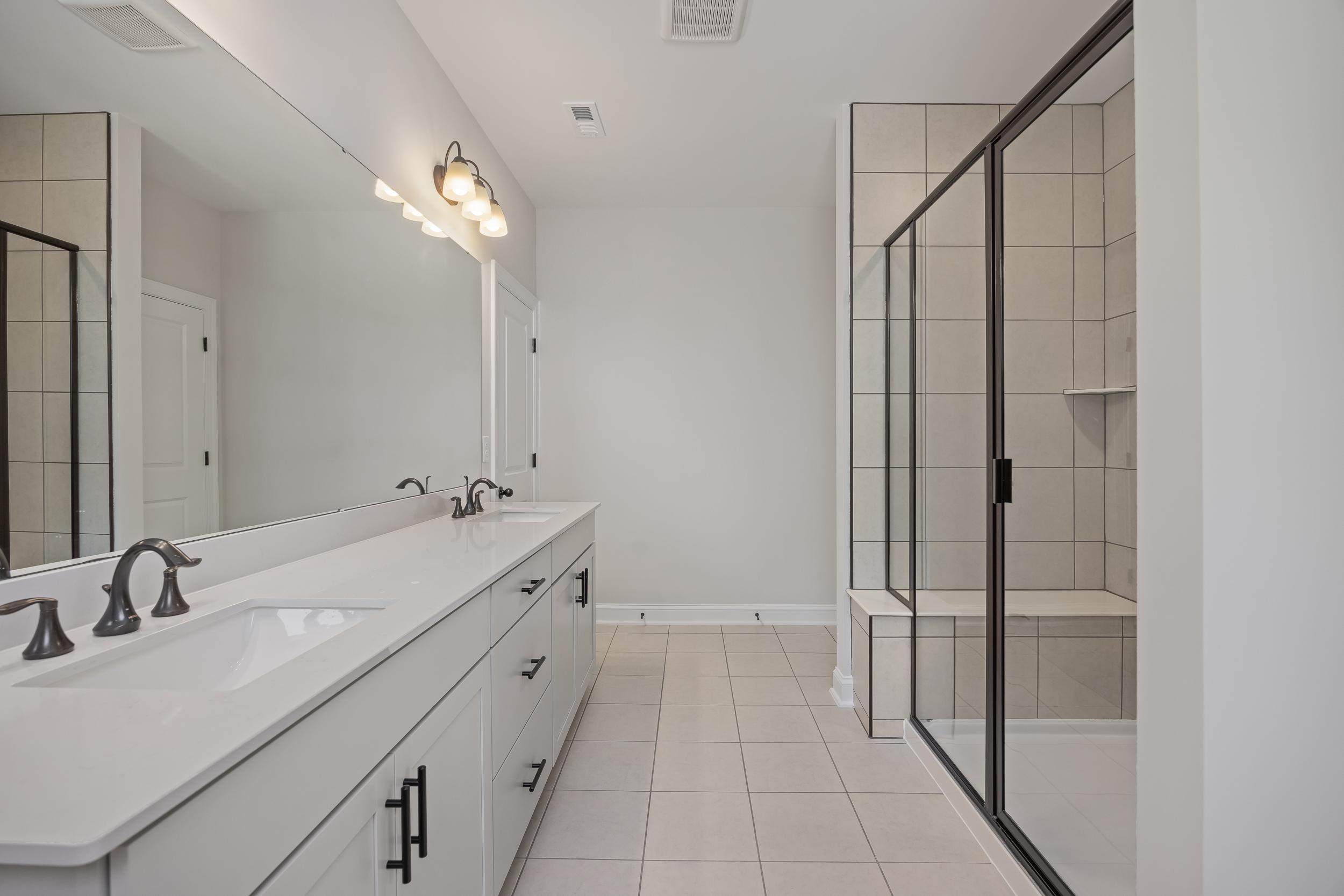 Spacious primary bathroom in Rockport, Wake Forest NC with double vanity, frameless glass shower, and neutral tile