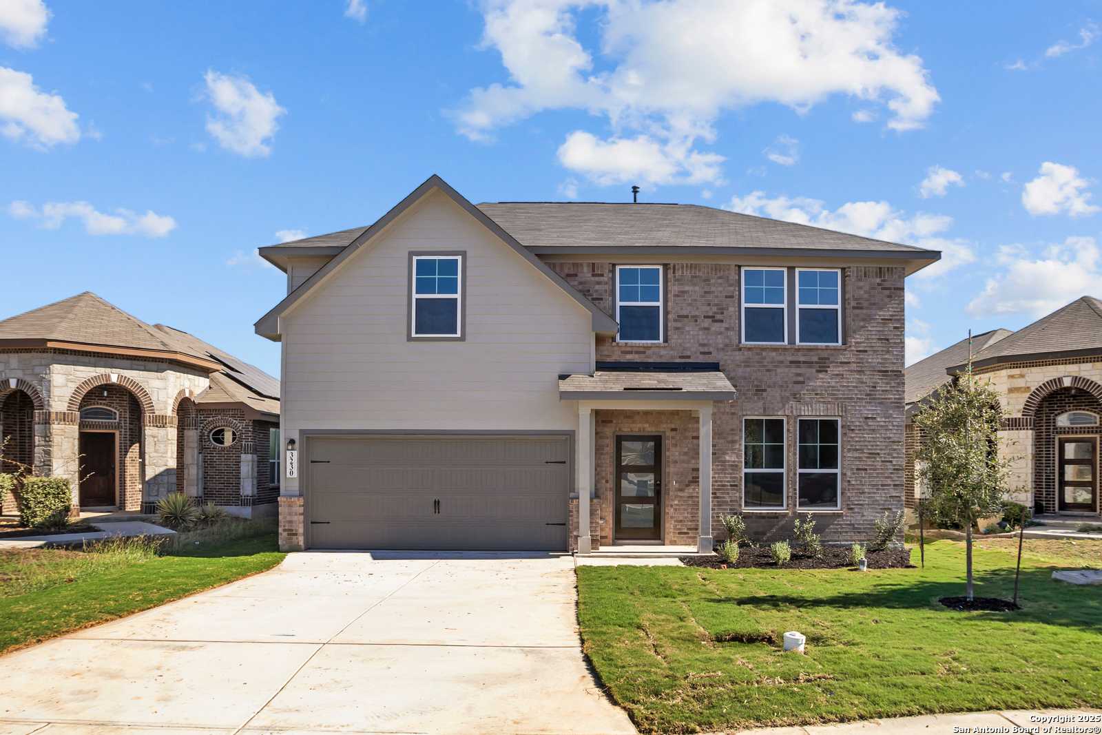 Two-story Murray F home by Davidson Homes: brick accents, two-car garage, driveway, and lush lawn in Horizon Pointe, Converse, TX