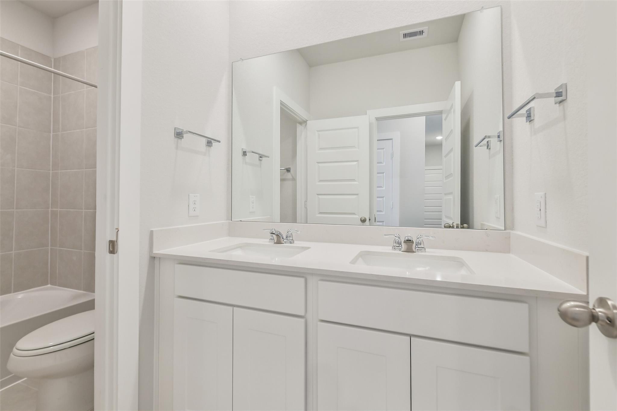 Modern master bathroom featuring double vanity sinks, large mirror, and tiled walk-in shower in Davidson Homes The Colorado F, Cleveland, Texas