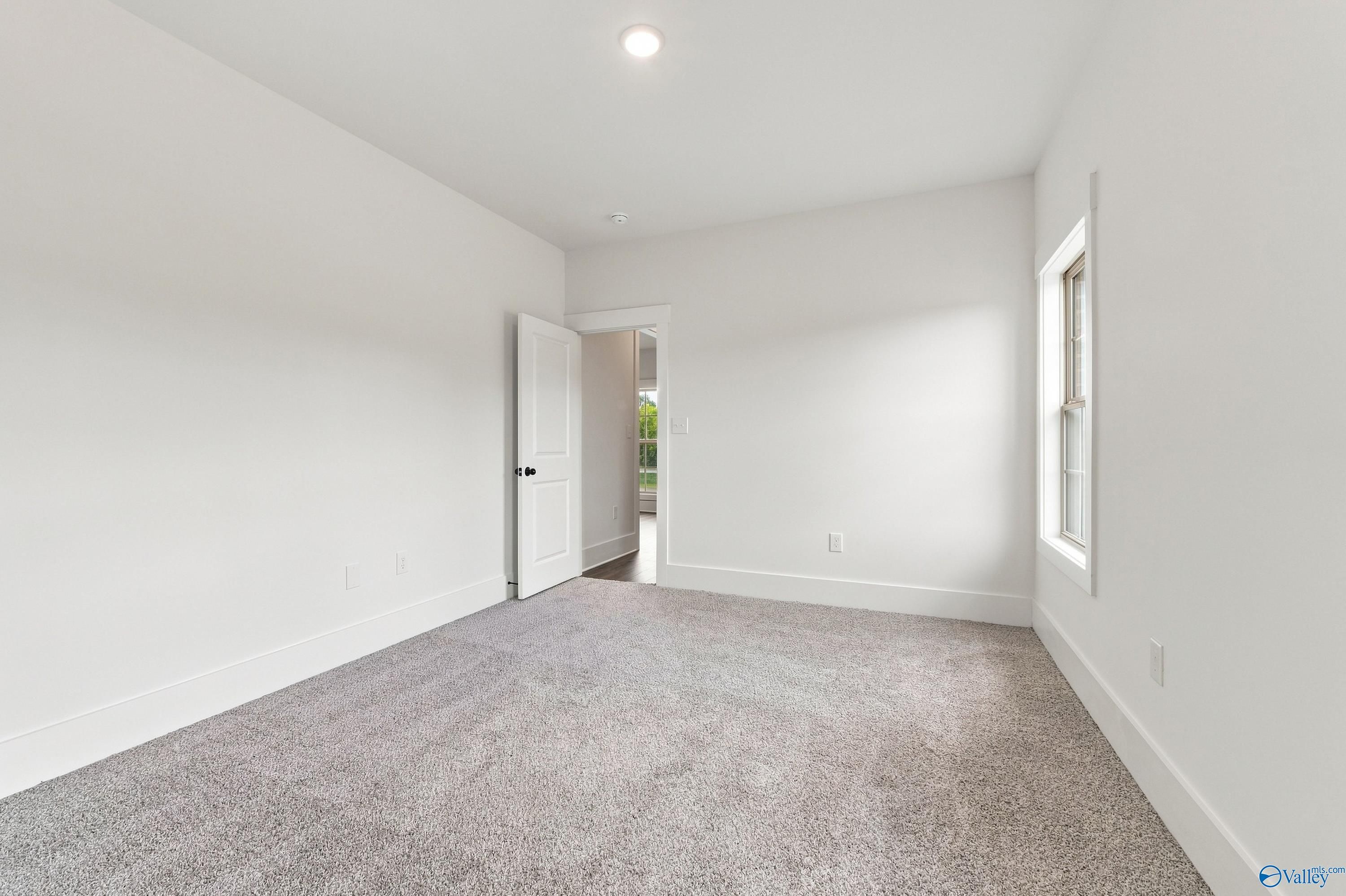 Bright empty bedroom with carpet, white walls, and natural light in Davidson Homes The Valencia floor plan, Huntsville, Alabama