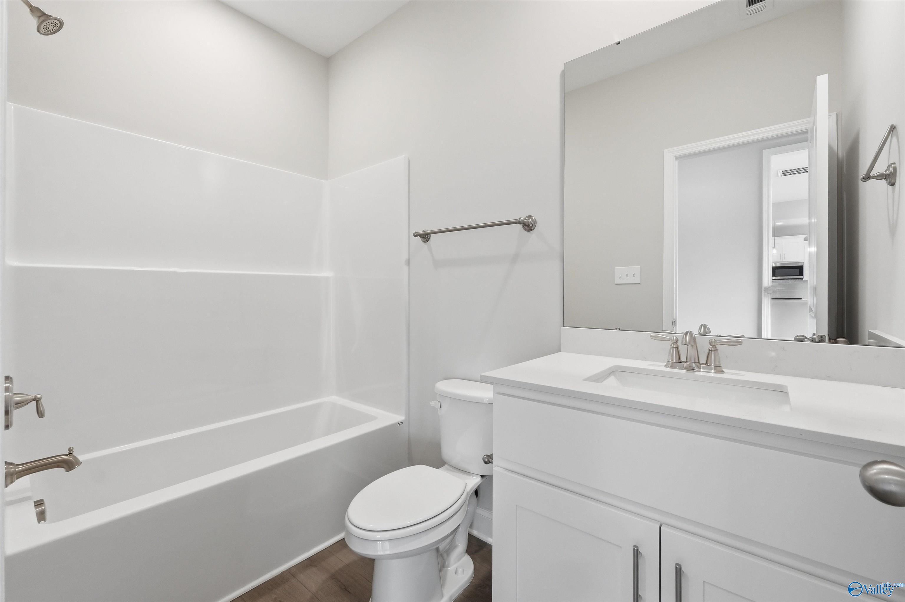 Modern bathroom with white vanity, tub-shower combo, and large mirror in The Shelby D floor plan, Evergreen Mill, Madison.