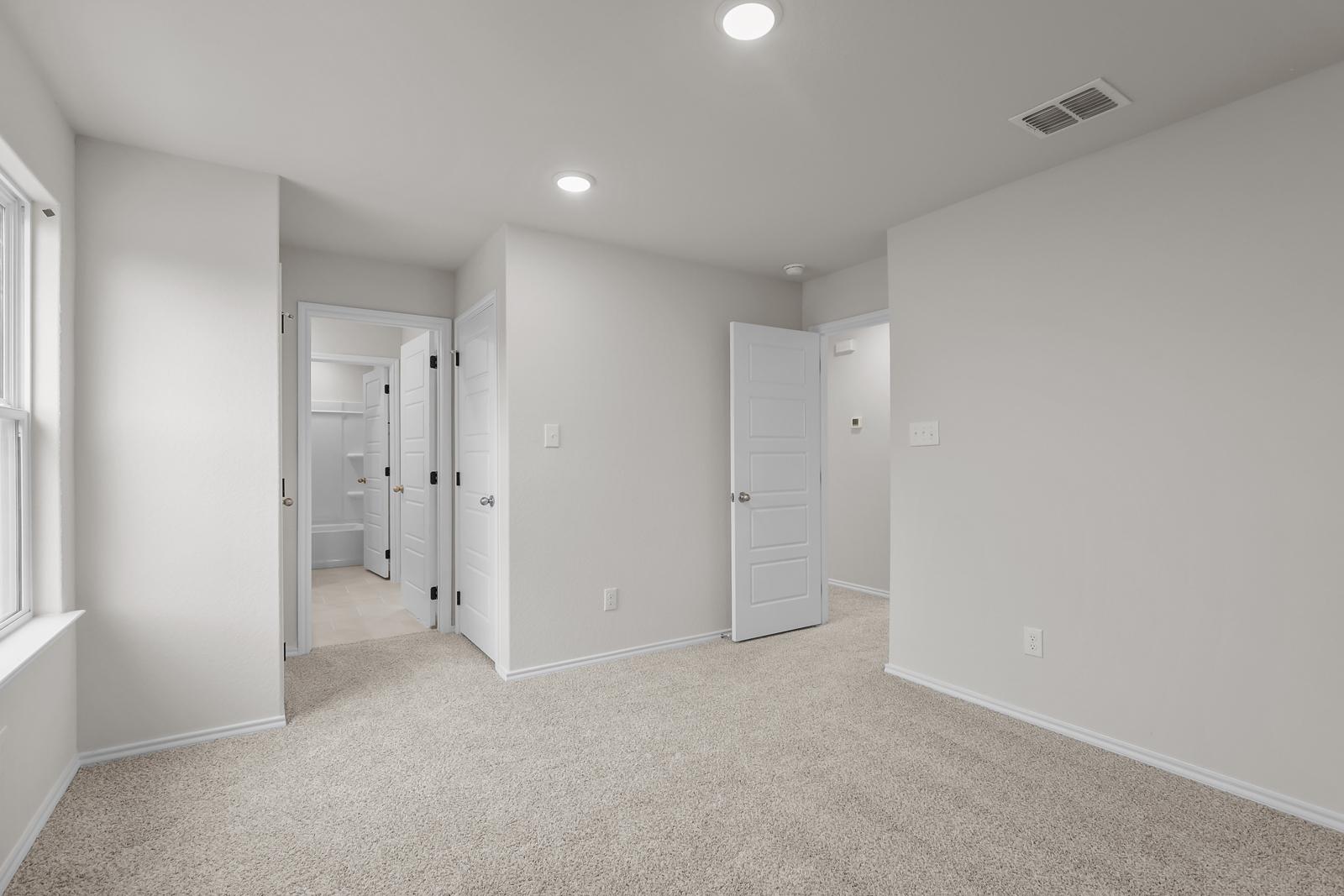 Spacious bedroom in The Sequoia C floor plan featuring neutral carpet, recessed lighting, and an en-suite bathroom entrance.