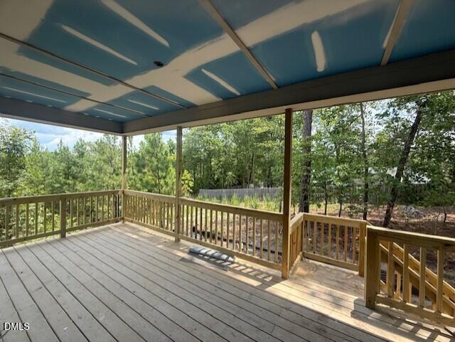 Unfinished covered deck with wooden railings overlooking a wooded backyard at The Birch II A in Montrose, Aberdeen, NC.