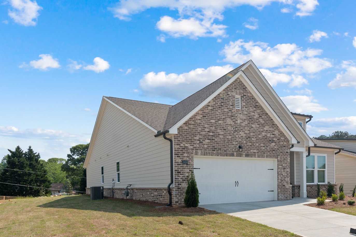 Side elevation of The Glenwood C single-story home in Hoschton, GA, with brick accents, beige siding, and 2-car garage