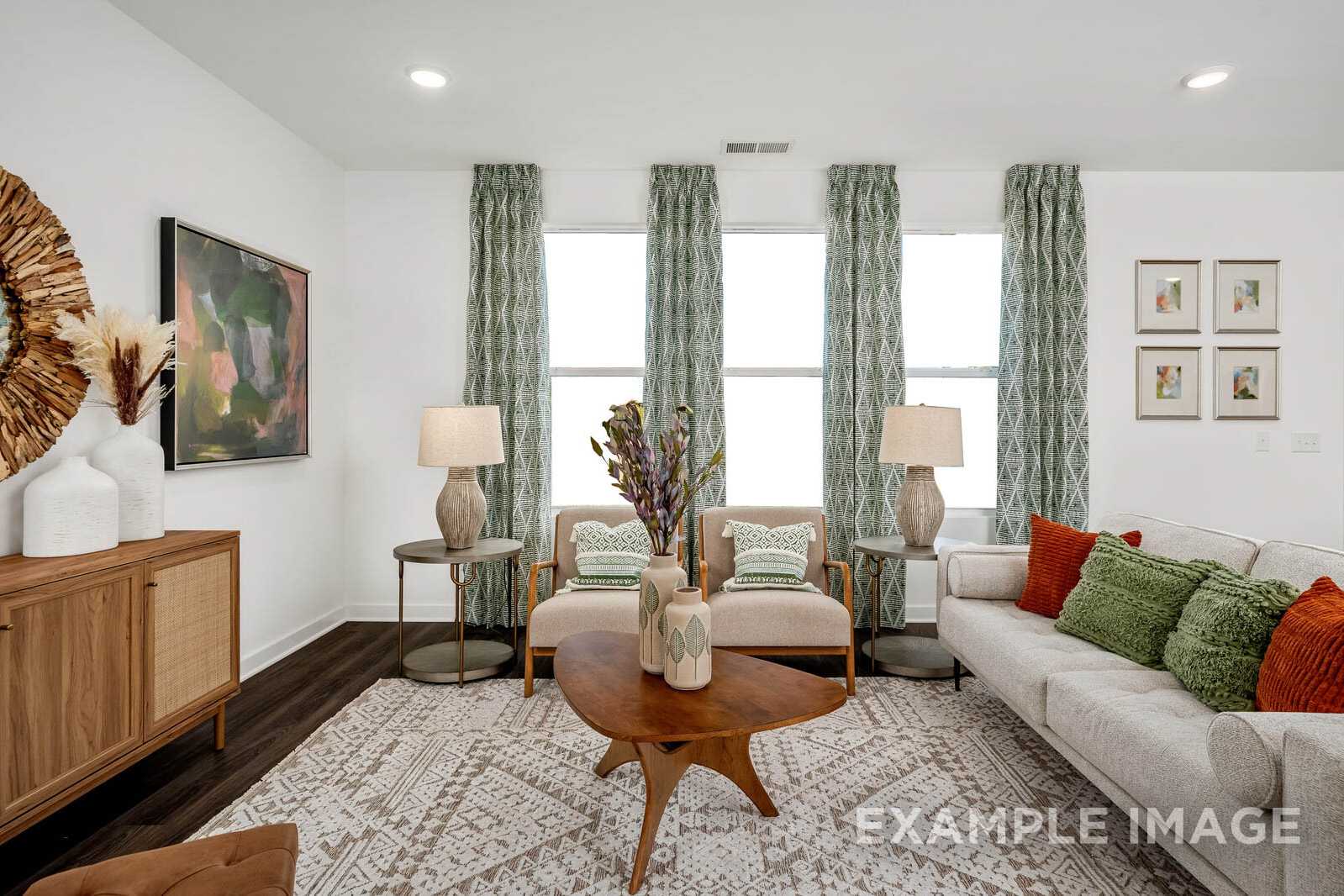 Spacious living room in The Gordon B home design featuring beige sofa, green pillows, wooden coffee table, and large windows