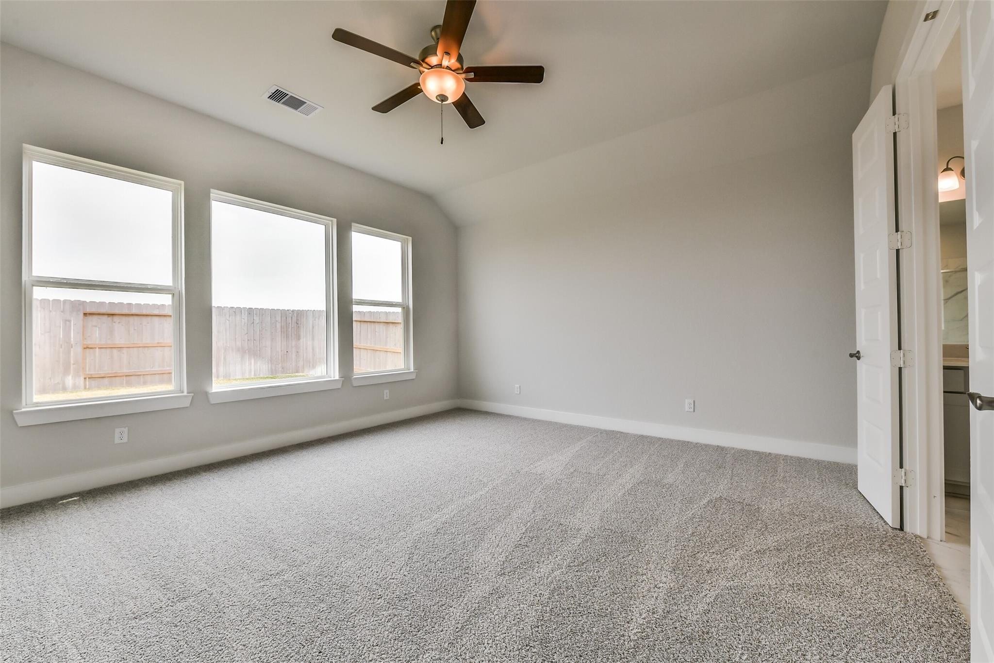 Spacious secondary bedroom with large windows, ceiling fan, and en-suite door in Davidson Homes The George A, Lago Mar, Texas City