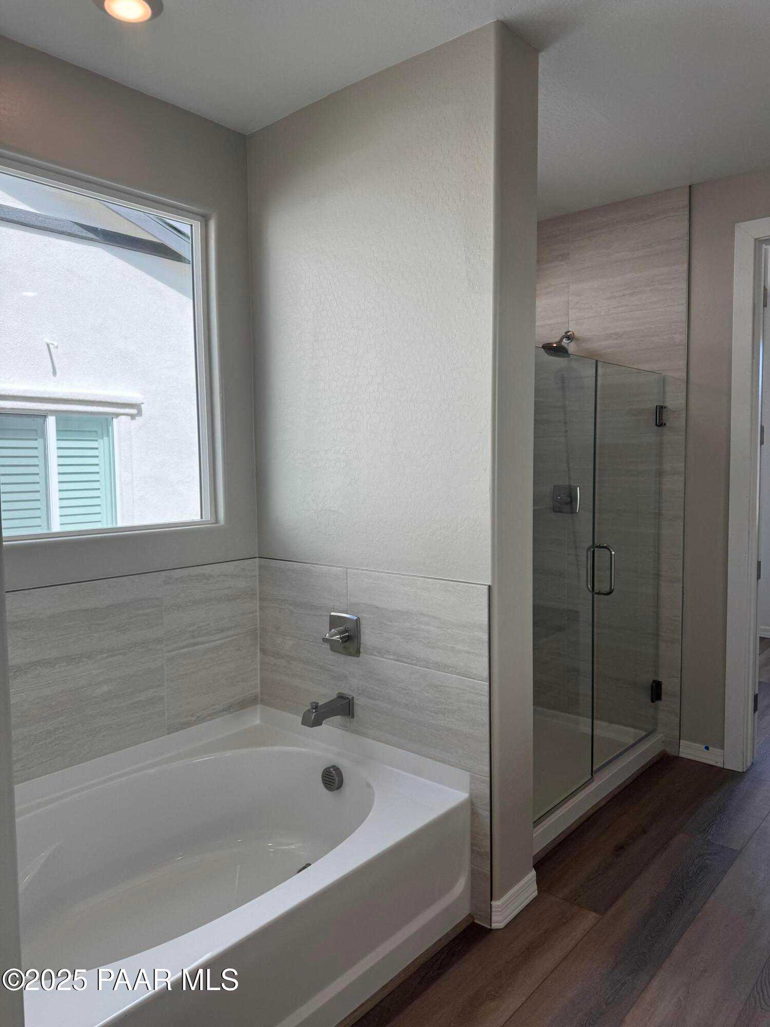 Elegant master bathroom featuring deep soaking tub, glass-enclosed walk-in shower, and shiplap walls in Davidson Homes The Monarch A, Prescott, AZ