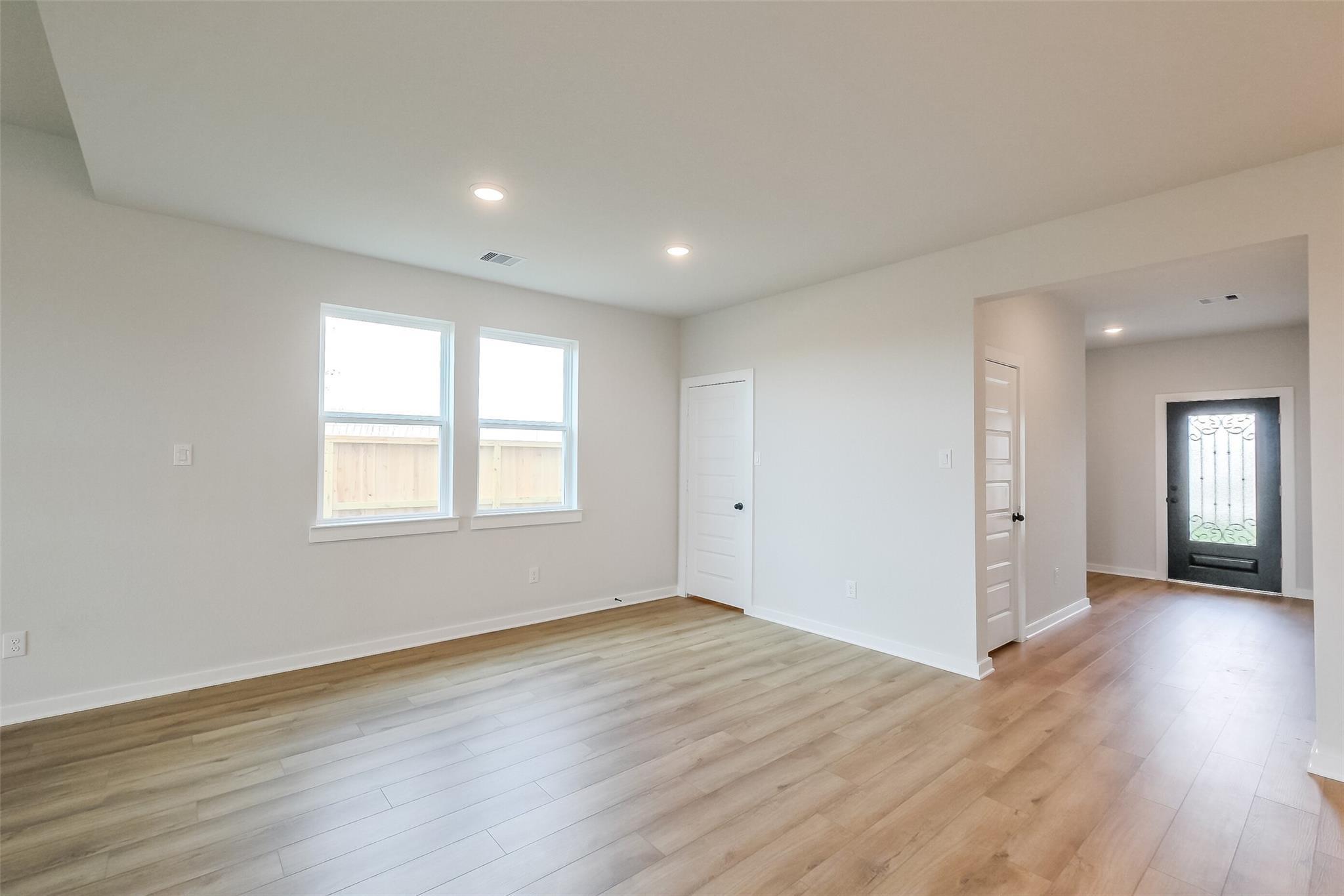 Bright bedroom featuring large windows, closet door, and laminate wood floors in Davidson Homes The Tierra B, Beasley, Texas
