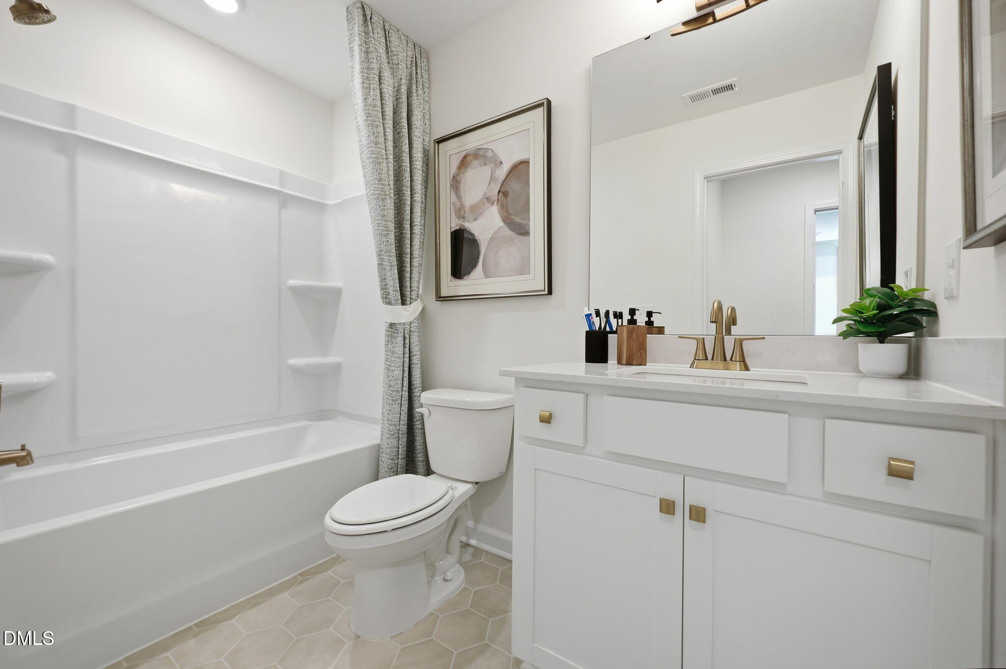 Modern bathroom with white vanity, brass fixtures, and tub-shower combo in The Aspen B home at Wendell Ridge, NC.