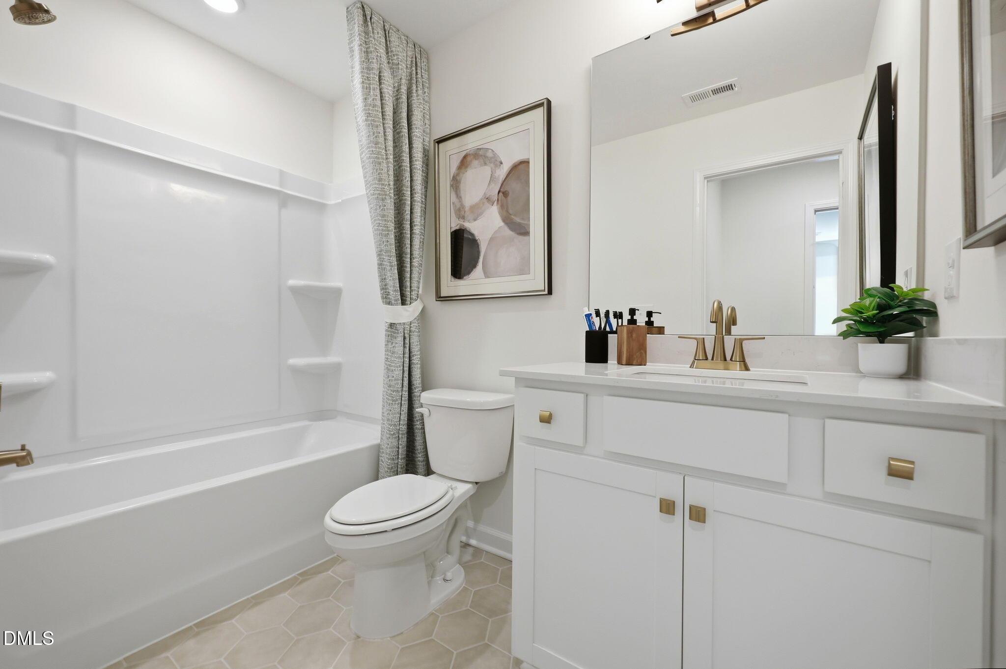 Modern bathroom with white vanity, brass fixtures, and tub-shower combo in The Aspen B home at Wendell Ridge, NC.