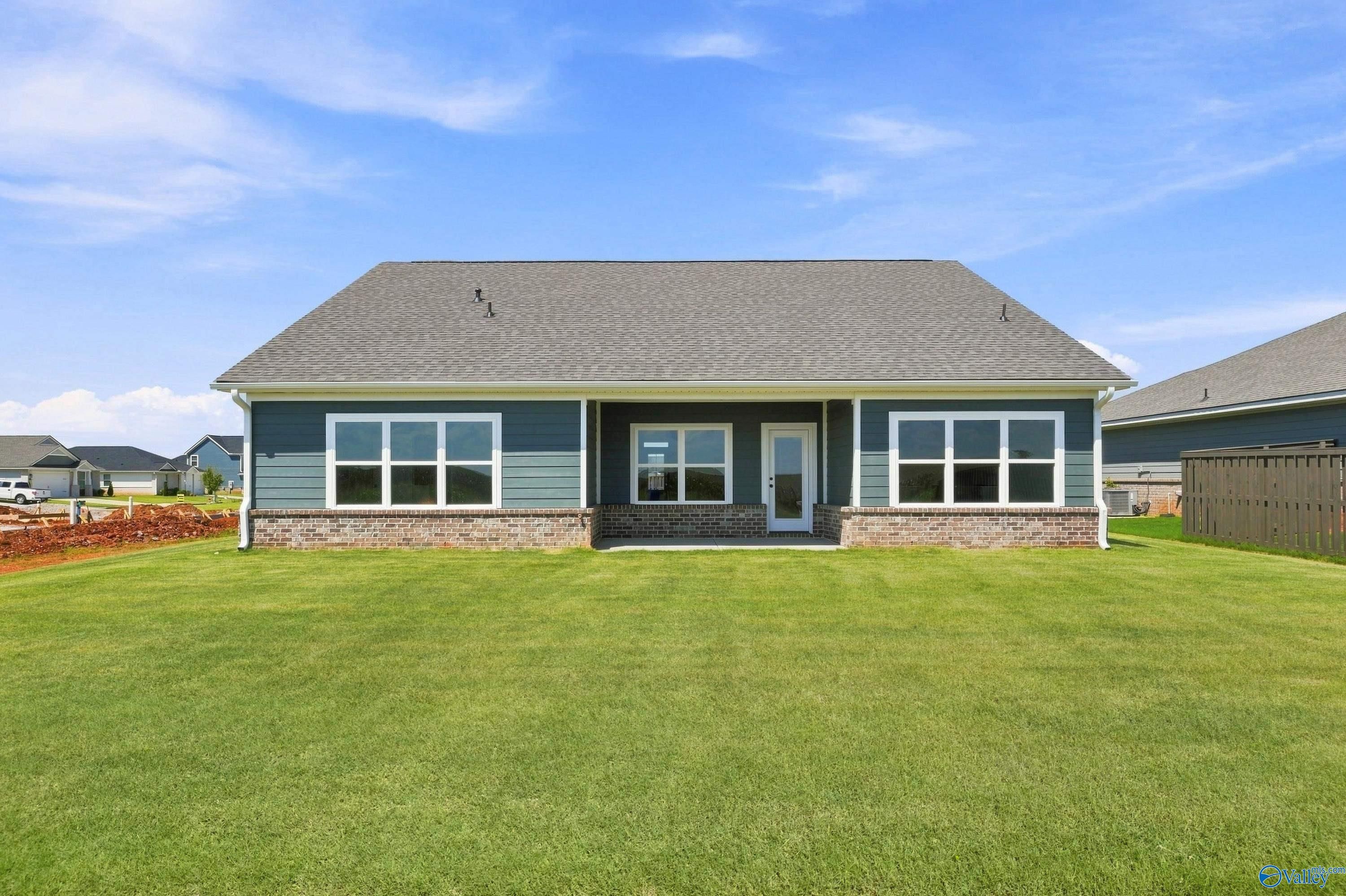 Rear exterior of one-story blue-sided home with covered patio and spacious fenced backyard at Anderson Farm, Athens, Alabama