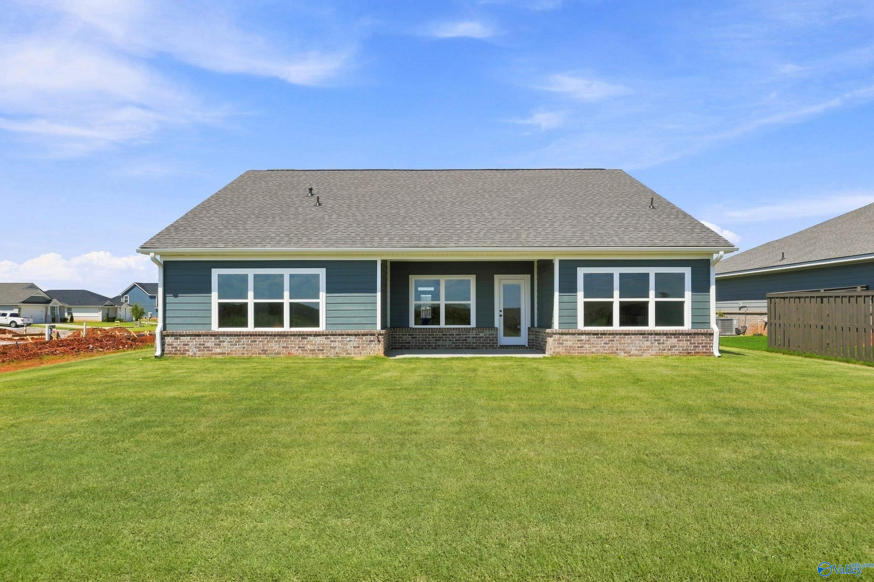 Rear exterior of one-story blue-sided home with covered patio and spacious fenced backyard at Anderson Farm, Athens, Alabama