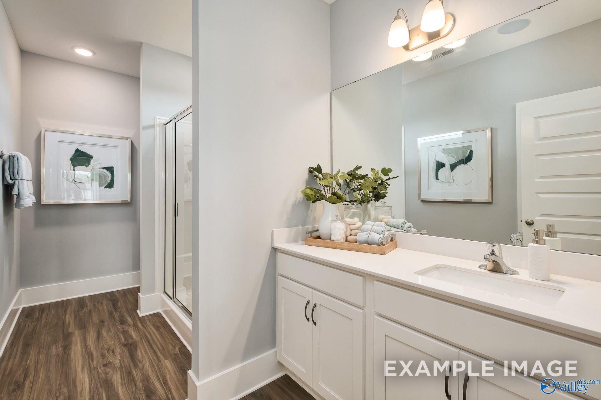 Bright white master bathroom vanity with large mirror and glass shower in The Daphne D plan, Wood Trail, Toney, Alabama