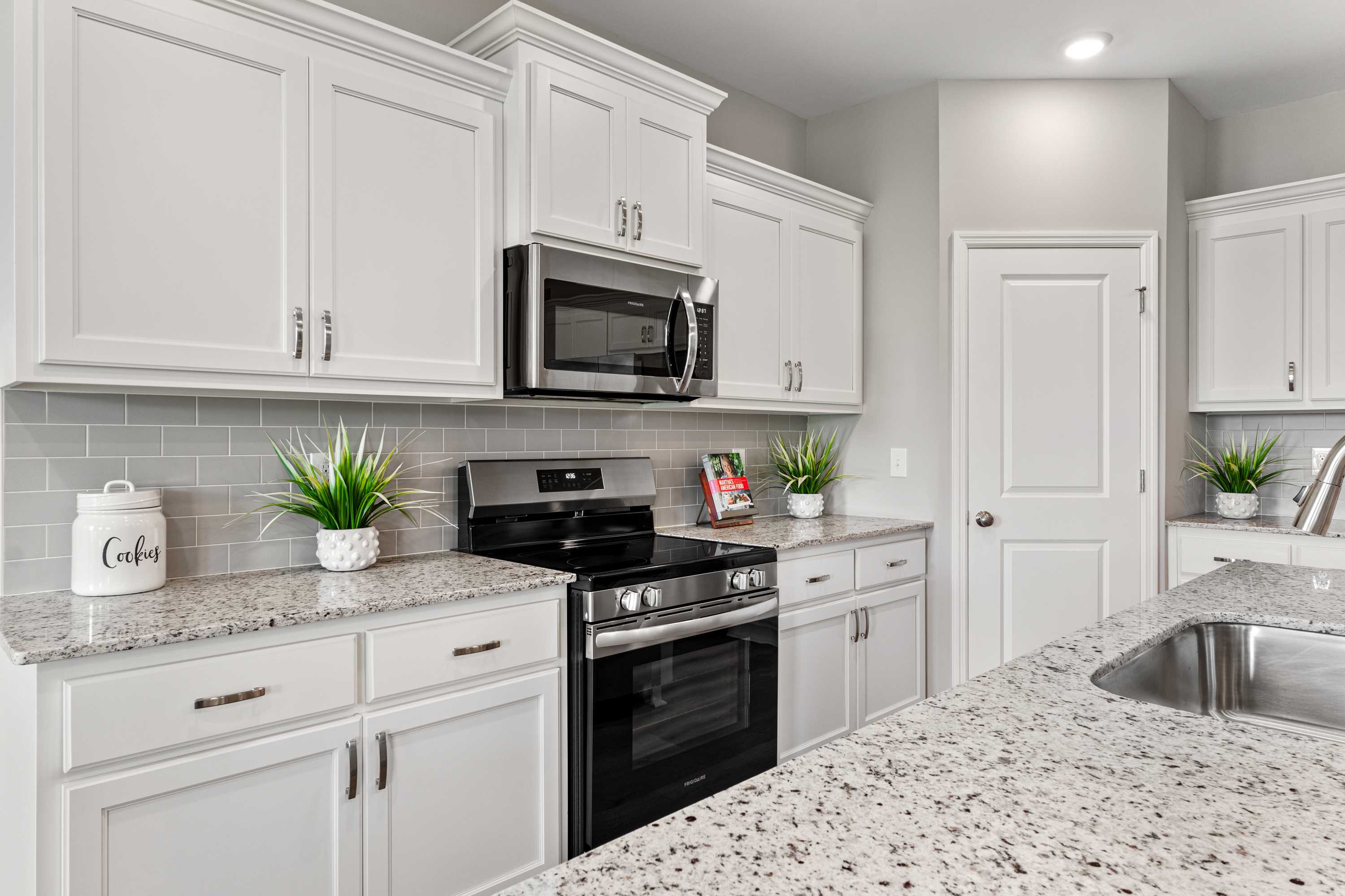 Modern white kitchen with granite counters, subway tile backsplash, and stainless appliances at Forest Glen in Hazel Green AL