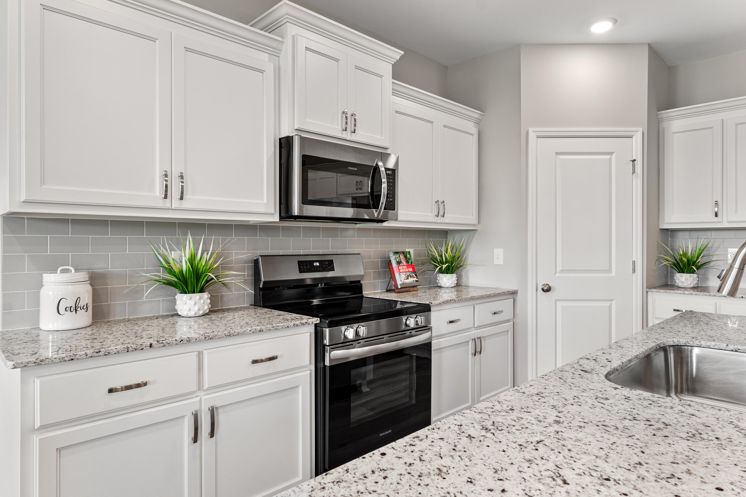Modern white kitchen with granite counters, subway tile backsplash, and stainless appliances at Forest Glen in Hazel Green AL