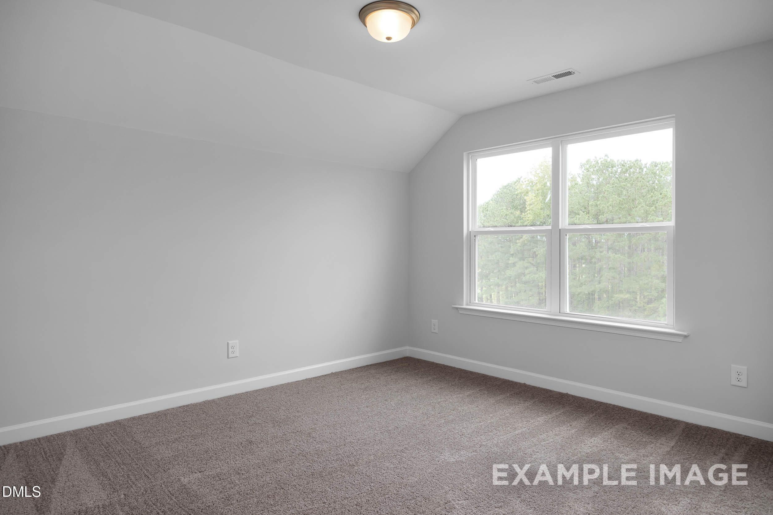 Spacious upstairs bedroom with vaulted ceiling, large windows overlooking trees, gray walls, and carpet in Davidson Homes The Ash B, Lillington, NC