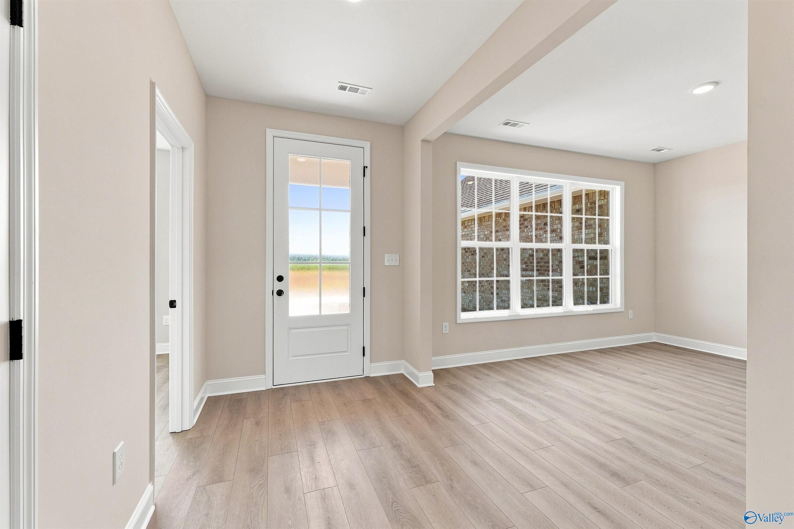 Bright living area with wood-look flooring and glass-paneled back door in The Oxford plan, Kendall Farms, Toney, Alabama.