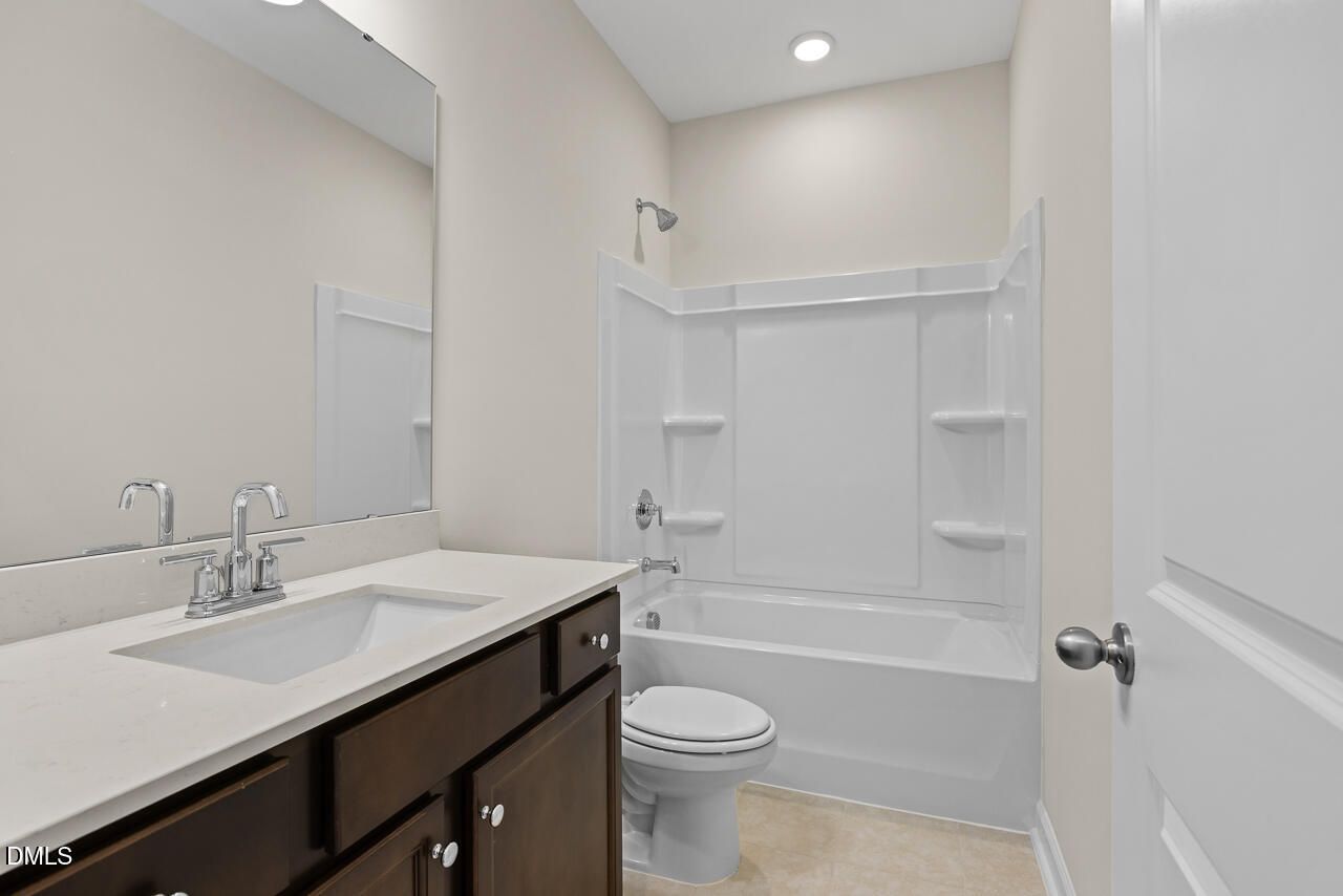 Full bathroom with white quartz vanity, dark wood cabinets, tub-shower combo, and toilet in Davidson Homes The Birch II C, Wake Forest
