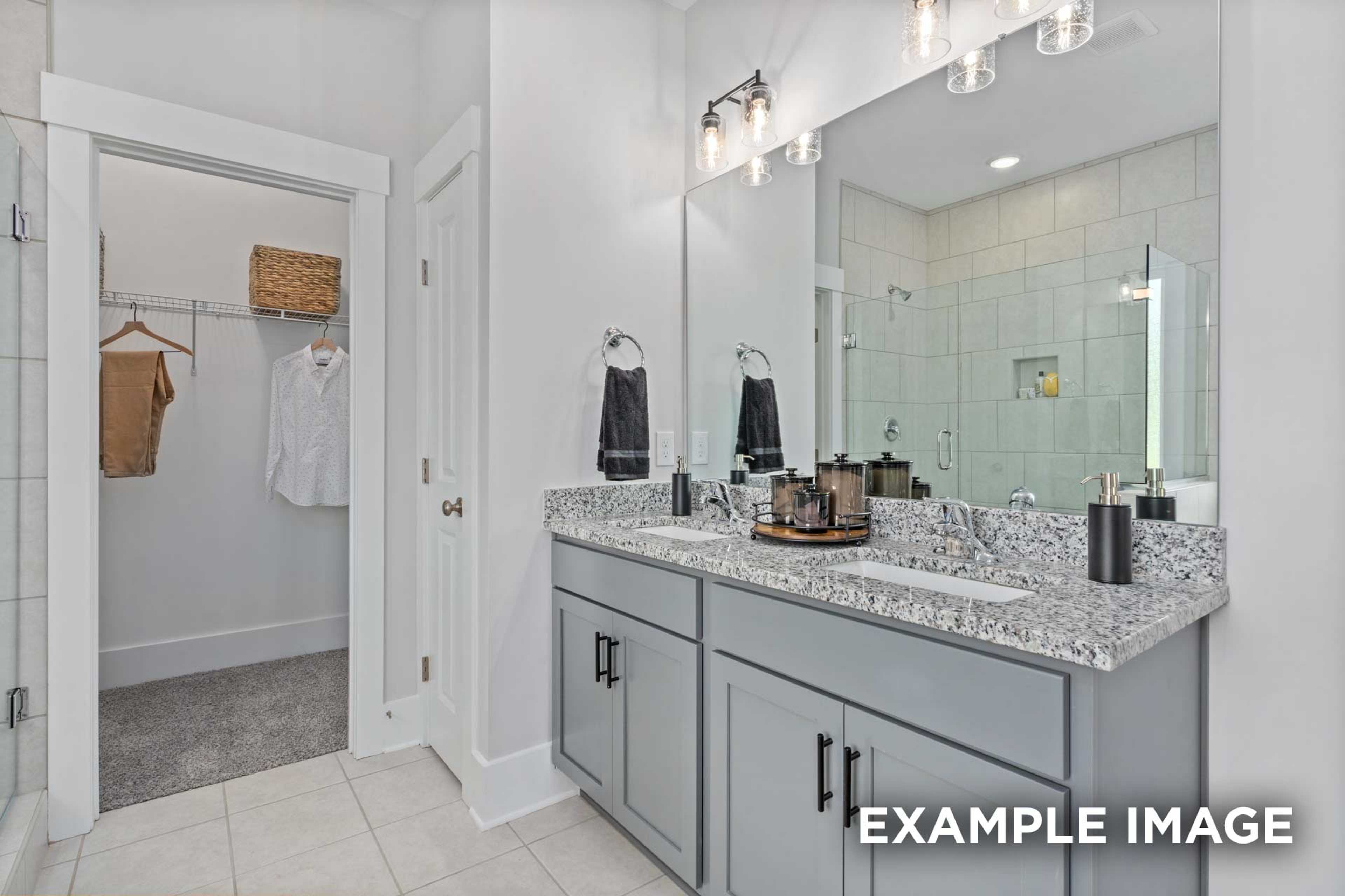 Spacious master bathroom in The Franklin C with double gray vanity, quartz counters, walk-in shower, and open closet