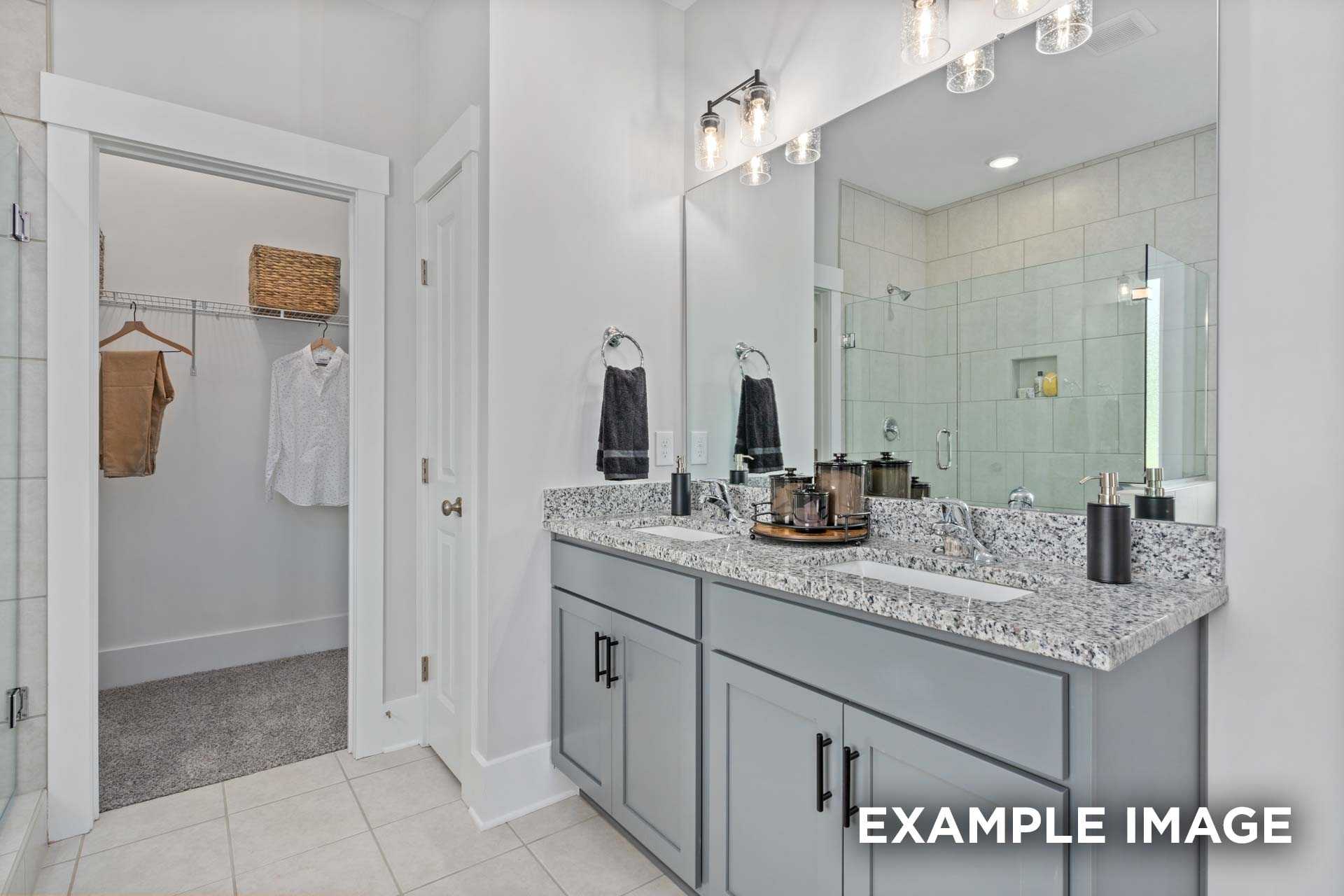 Spacious master bathroom in The Franklin C with double gray vanity, quartz counters, walk-in shower, and open closet