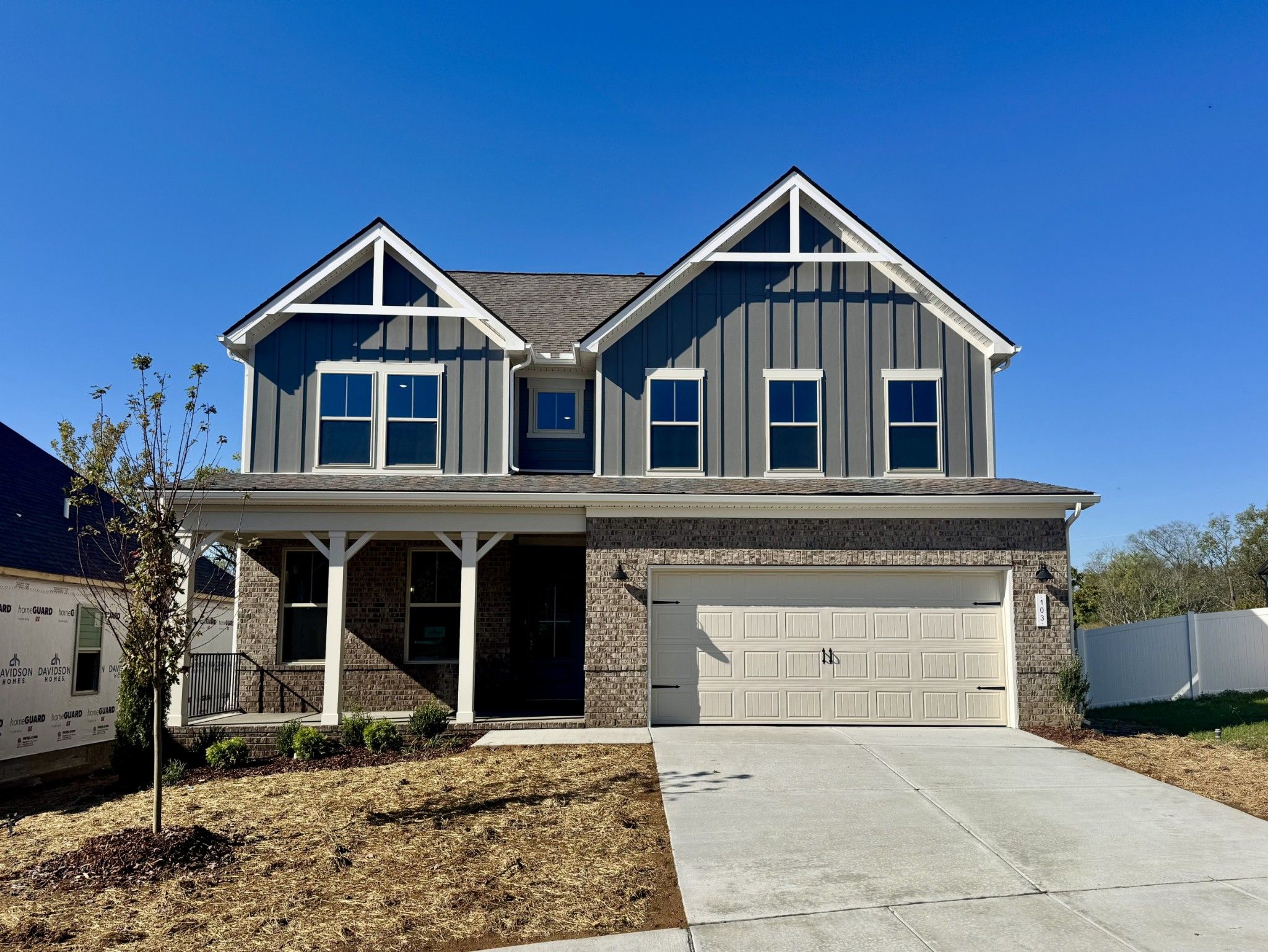 Two-story Davidson Homes The Willow B exterior with gray board-and-batten siding, covered porch, and 2-car garage in Woods Crossing, Gallatin, TN
