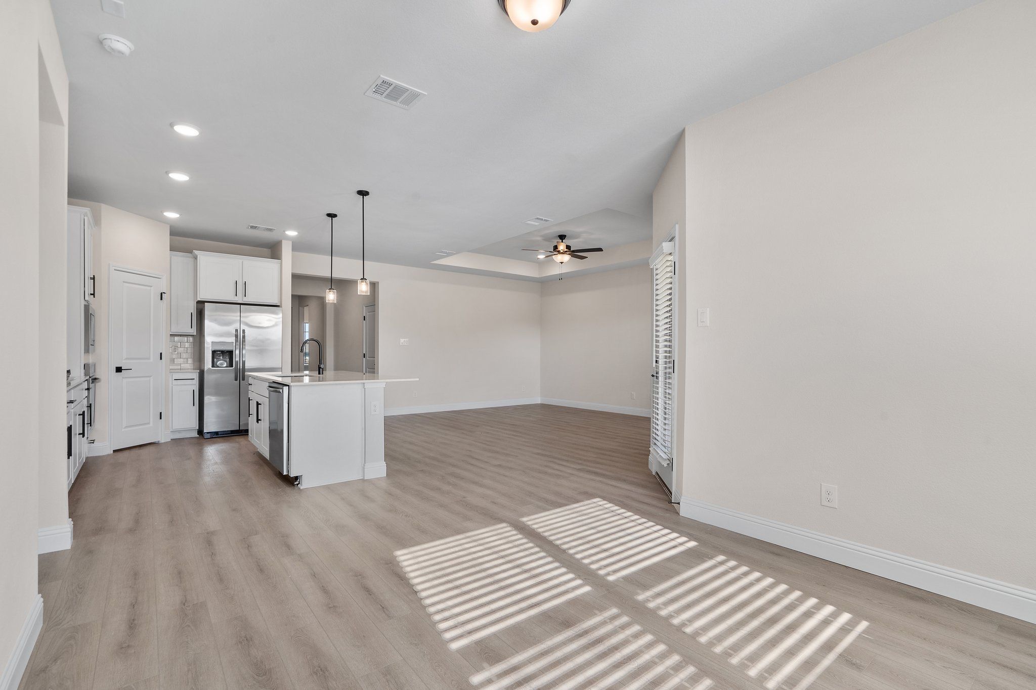 Open-concept kitchen and living area in The Holly F featuring white cabinetry, stainless appliances, and wood-style flooring.