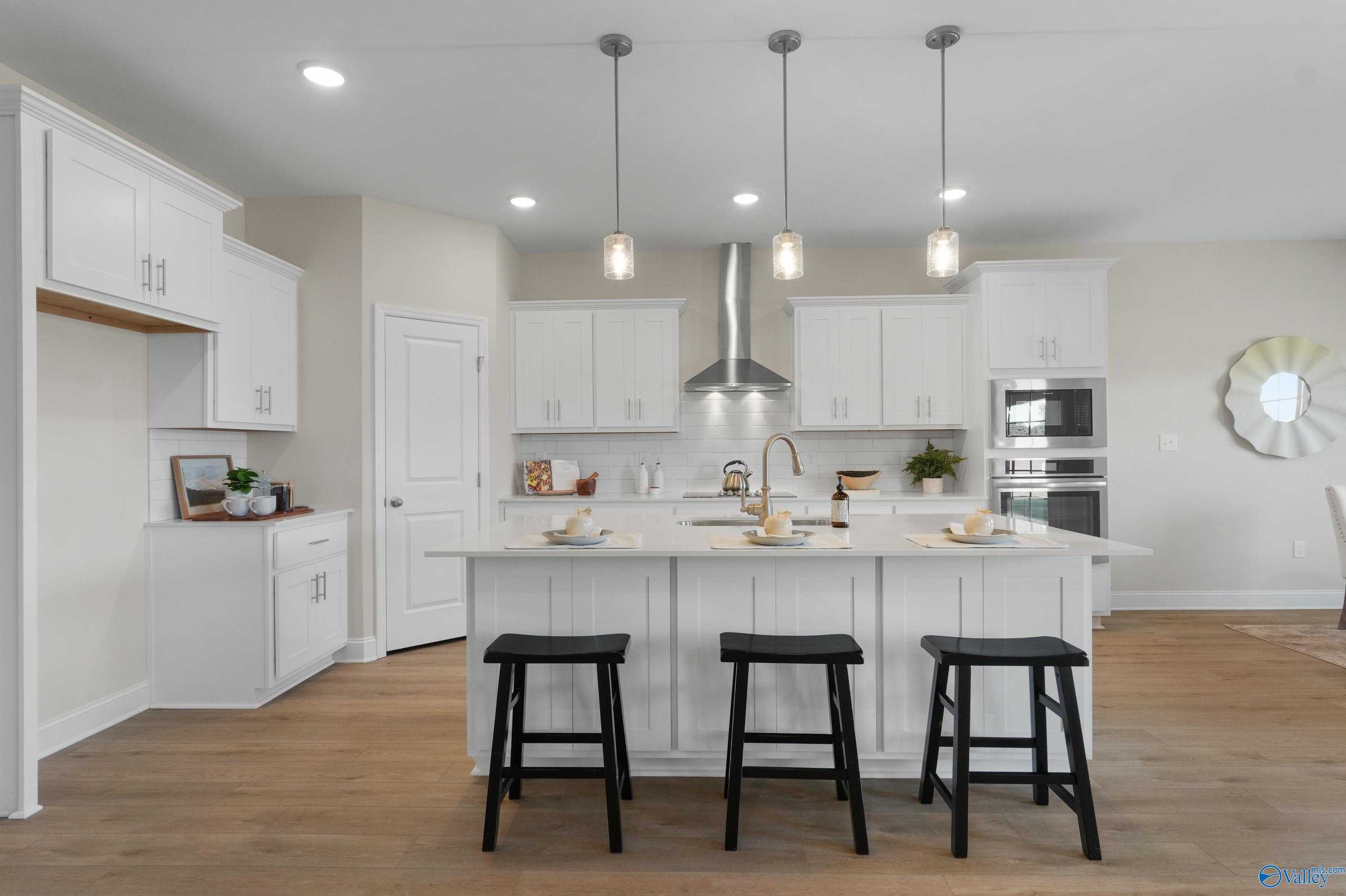 Modern white kitchen island with stainless steel appliances and pendant lights in Davidson Homes The Rockford B, Toney, Alabama