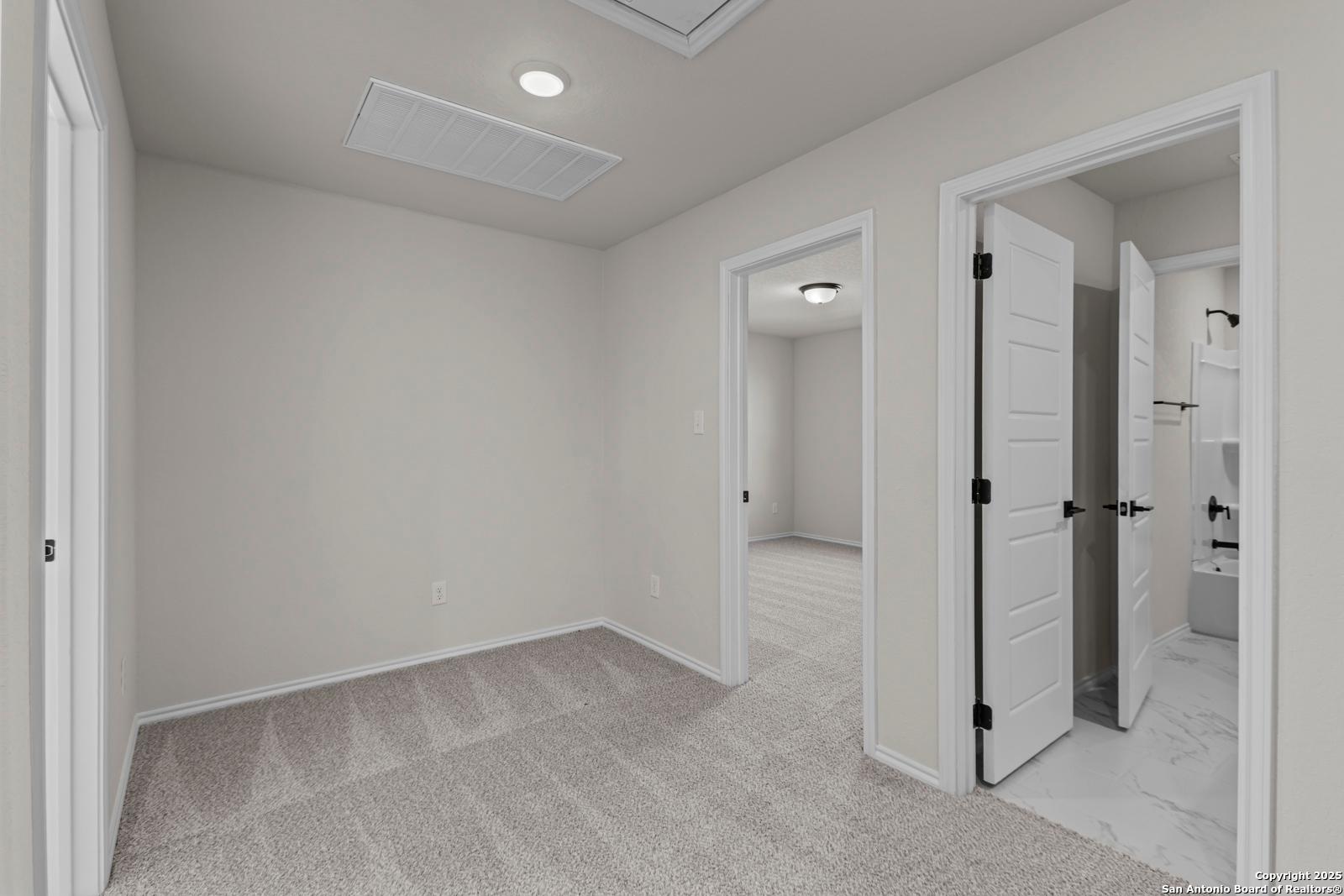 Spacious secondary bedroom with open en-suite bathroom door in Davidson Homes The Douglas C, Hannah Heights, Seguin, Texas