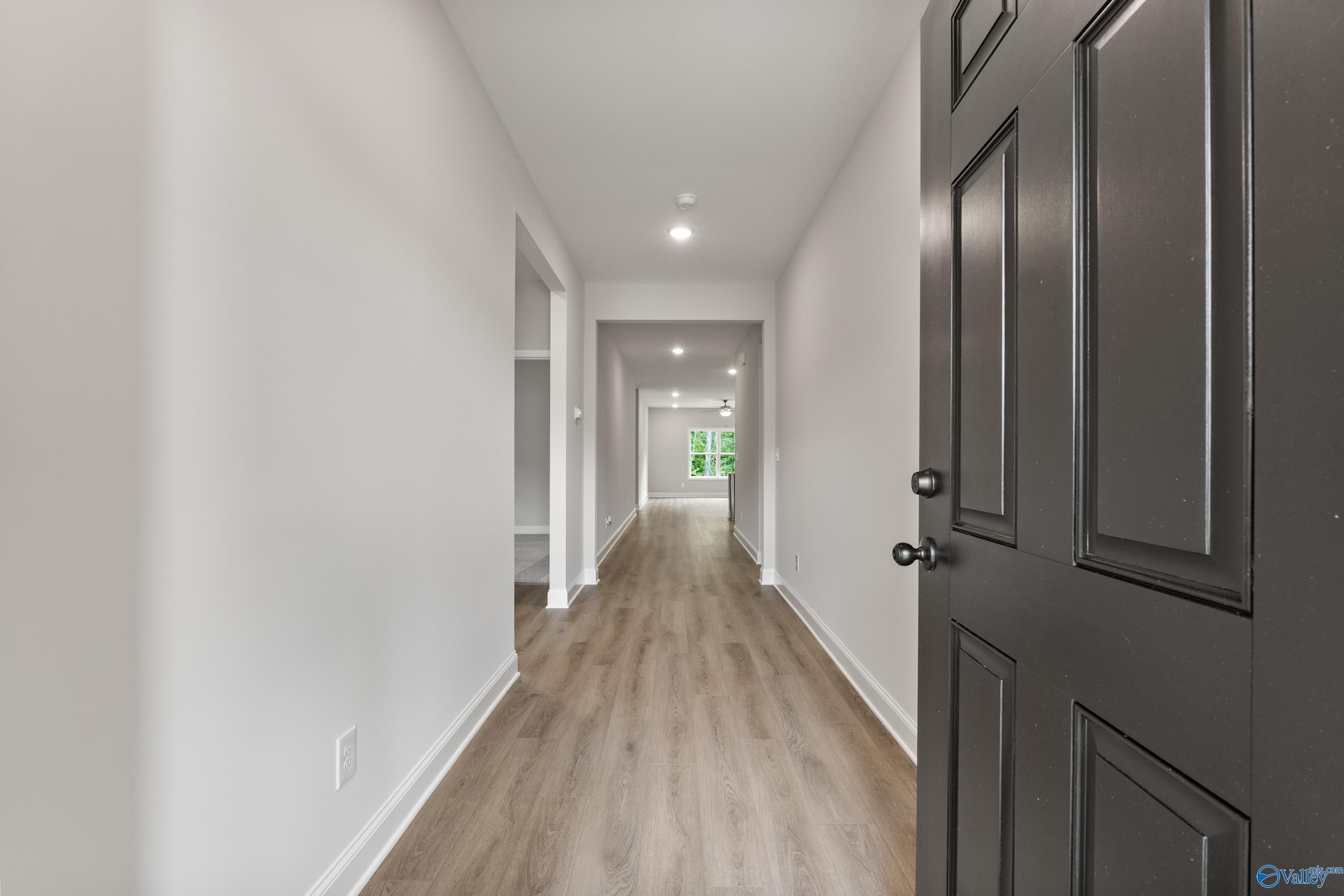 Spacious hallway with light wood flooring, white walls, and interior doors in Davidson Homes The Daphne, 4-bedroom home in Spragins Cove, Huntsville, Alabama
