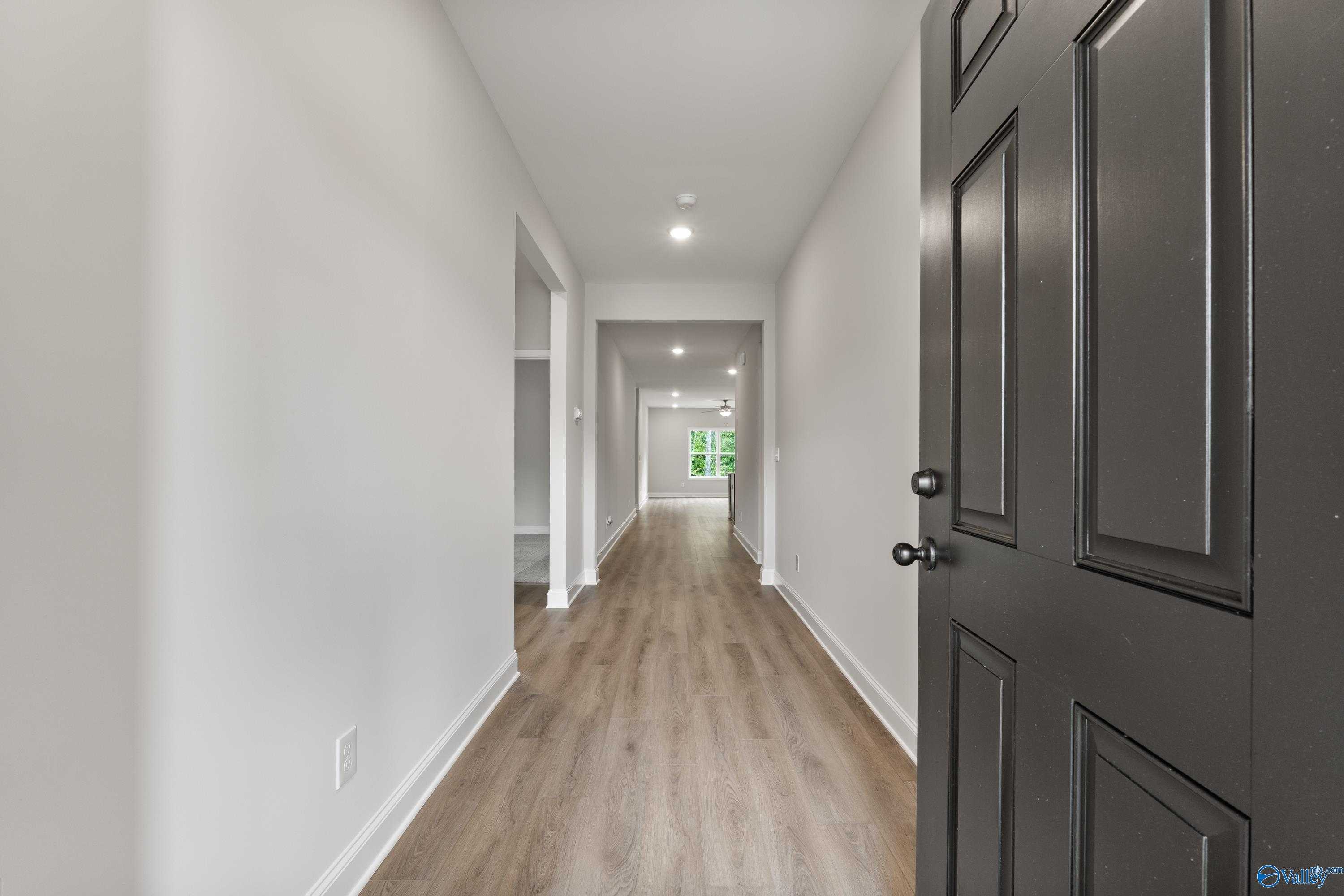 Spacious hallway with light wood flooring, white walls, and interior doors in Davidson Homes The Daphne, 4-bedroom home in Spragins Cove, Huntsville, Alabama