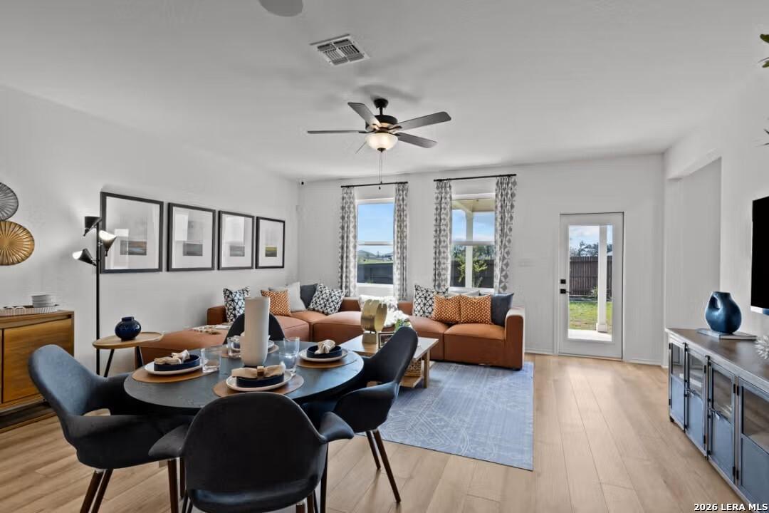 Open-concept living room with orange sofa, round dining table, ceiling fan, and backyard view in 4-bedroom Davidson Homes The Douglas C, Converse, Texas