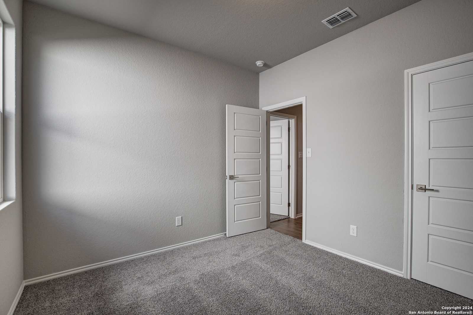 Spacious secondary bedroom with gray walls, carpet flooring, and en-suite door in Davidson Homes The Frio B, San Antonio